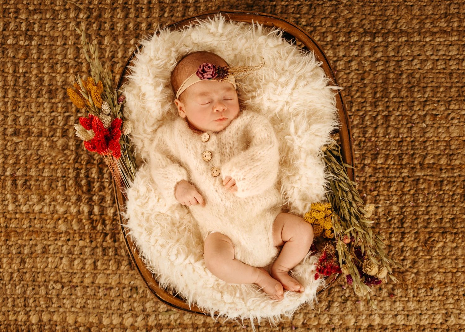 Seven sleeping newborn babies nestled in soft white fur blankets against a textured brown backdrop.