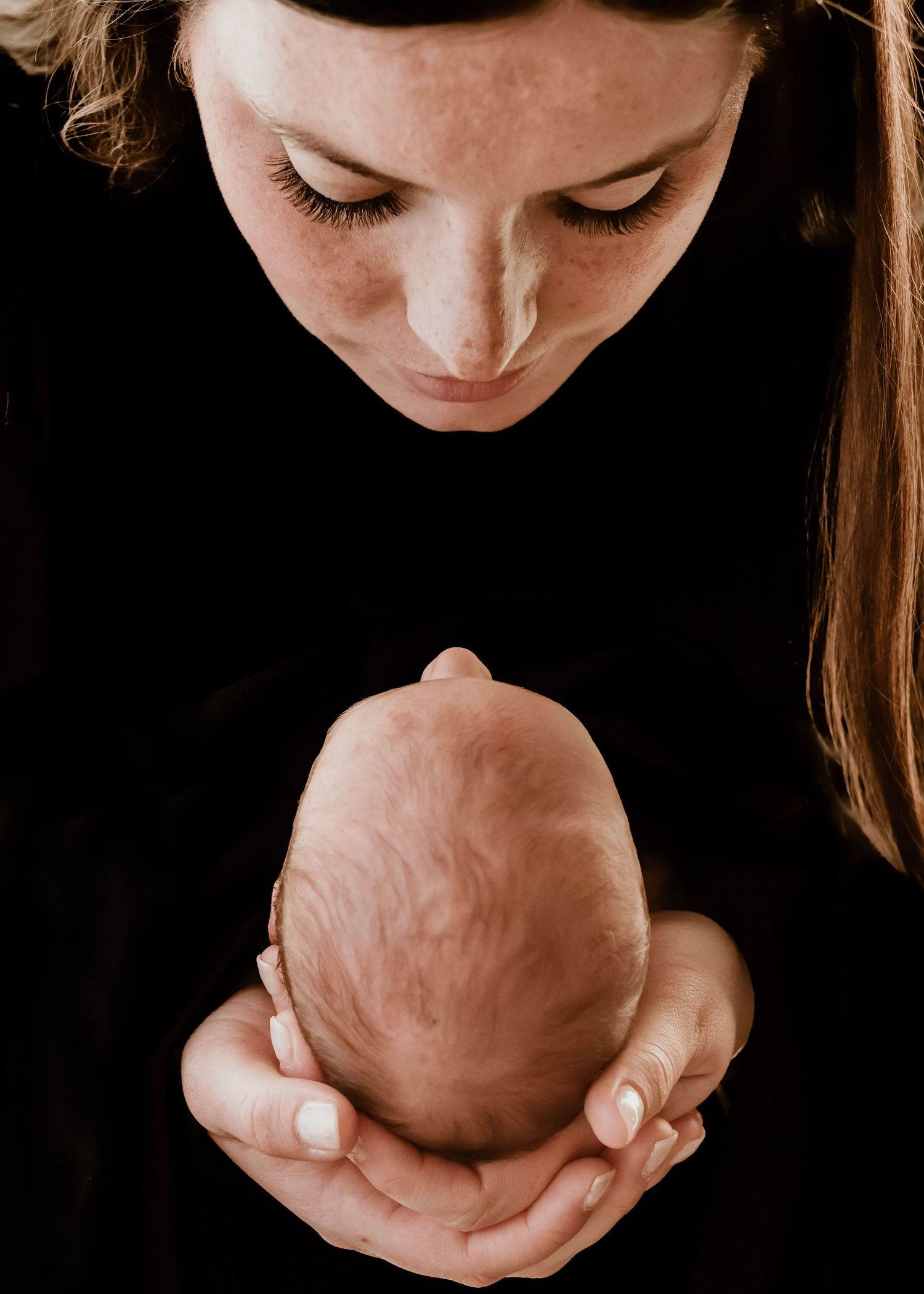 A progression of photos shows hands gently holding and cradling a newborn baby's head in intimate, tender moments.