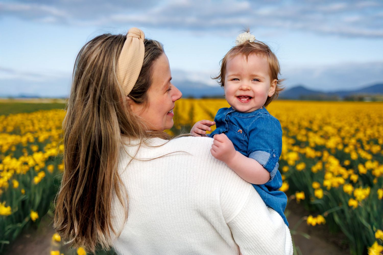 Parent and child share a joyful moment together in a vibrant yellow tulip field on a sunny spring day.