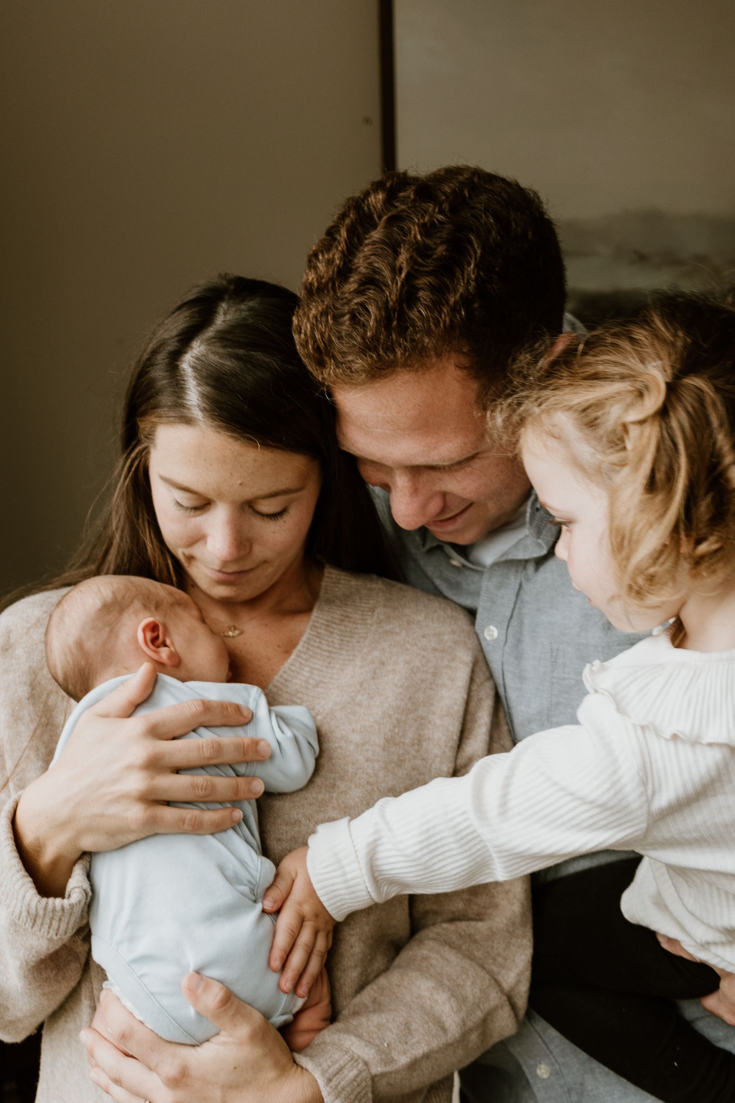 An intimate family moment as parents and sibling welcome their newborn baby while wearing cozy knit sweaters.