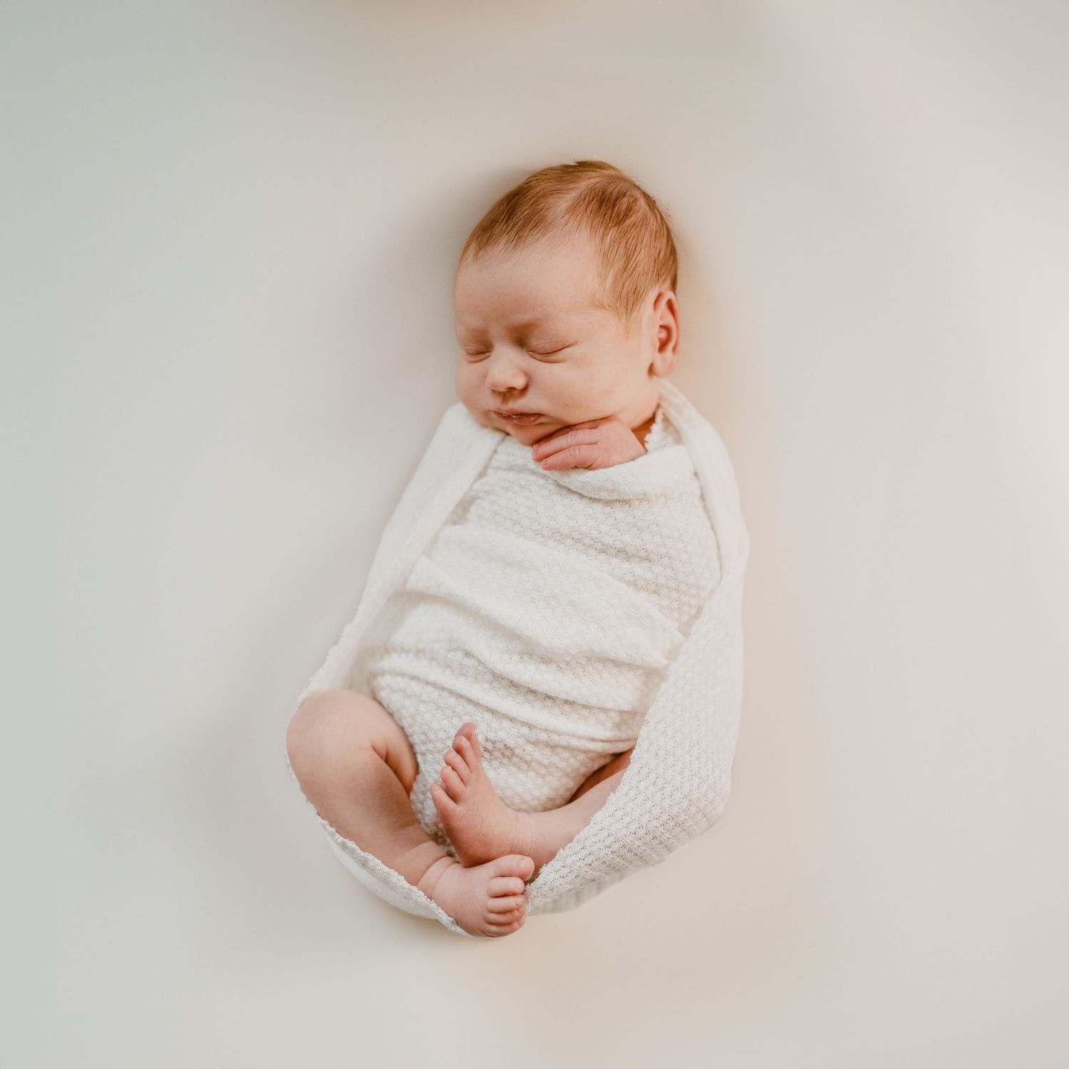 Sequence showing a peacefully sleeping infant swaddled in soft white blankets against a light neutral background.