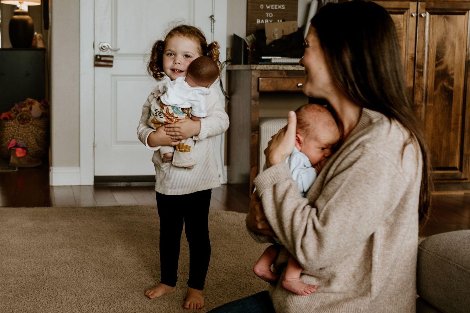A sweet candid moment between a baby and caregiver in matching cream outfits against a rustic wooden background.