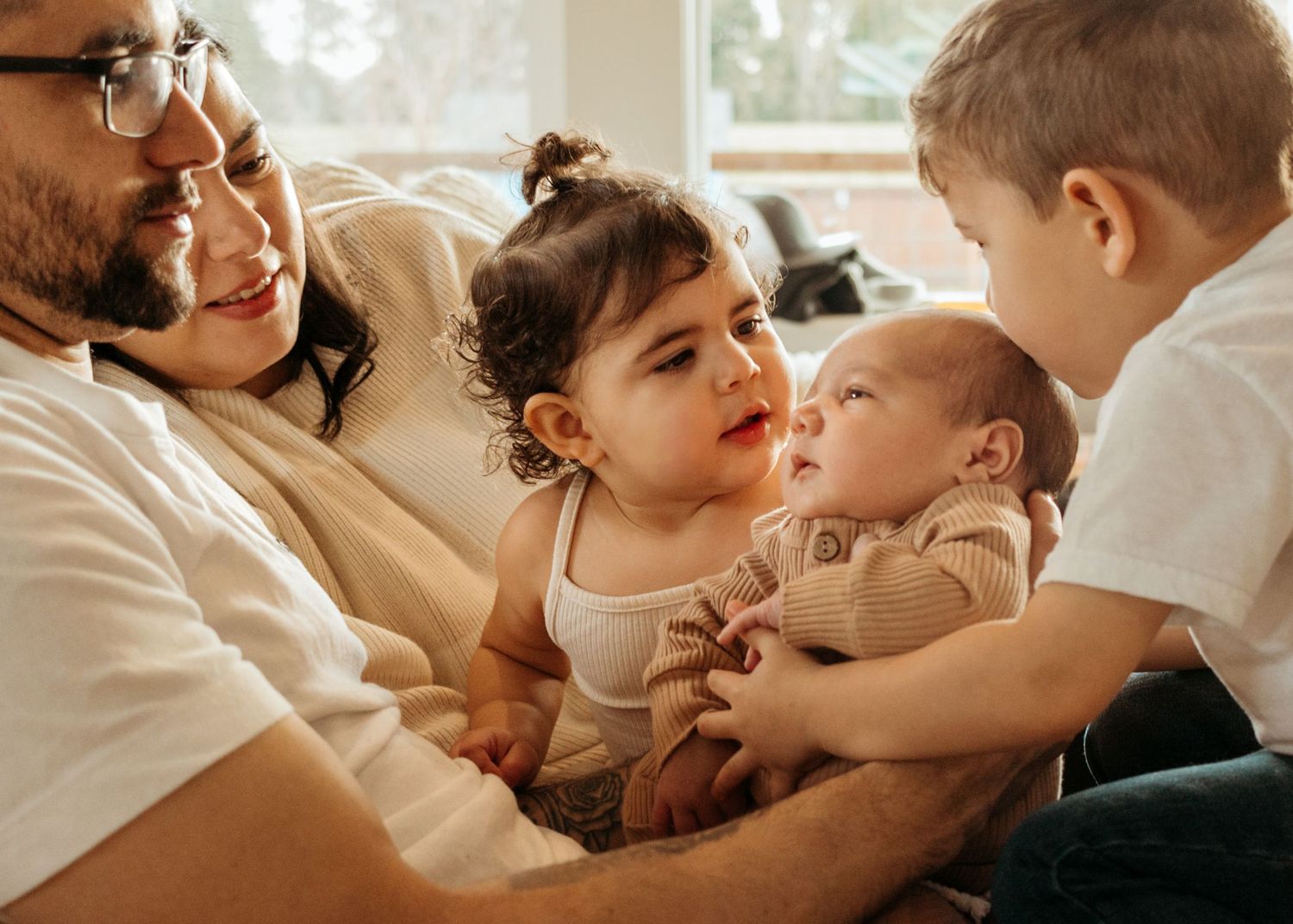 A loving family shares a tender moment together on the couch, laughing and bonding in warm natural light.