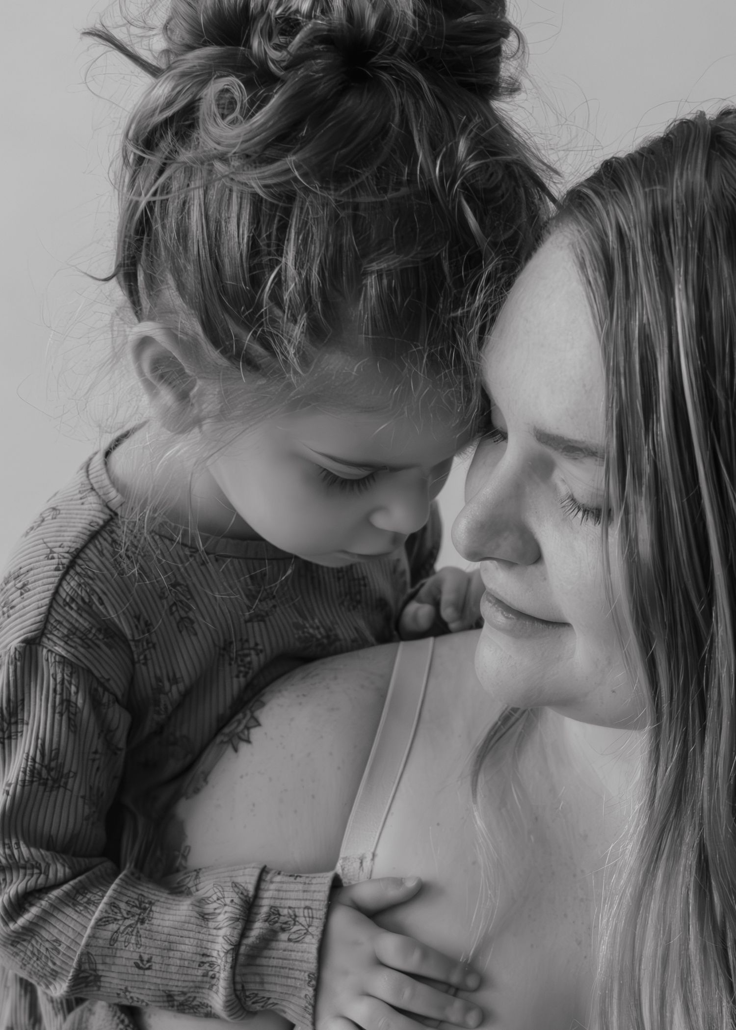 Black and white portrait capturing an intimate moment of tender affection and connection between mother and child.