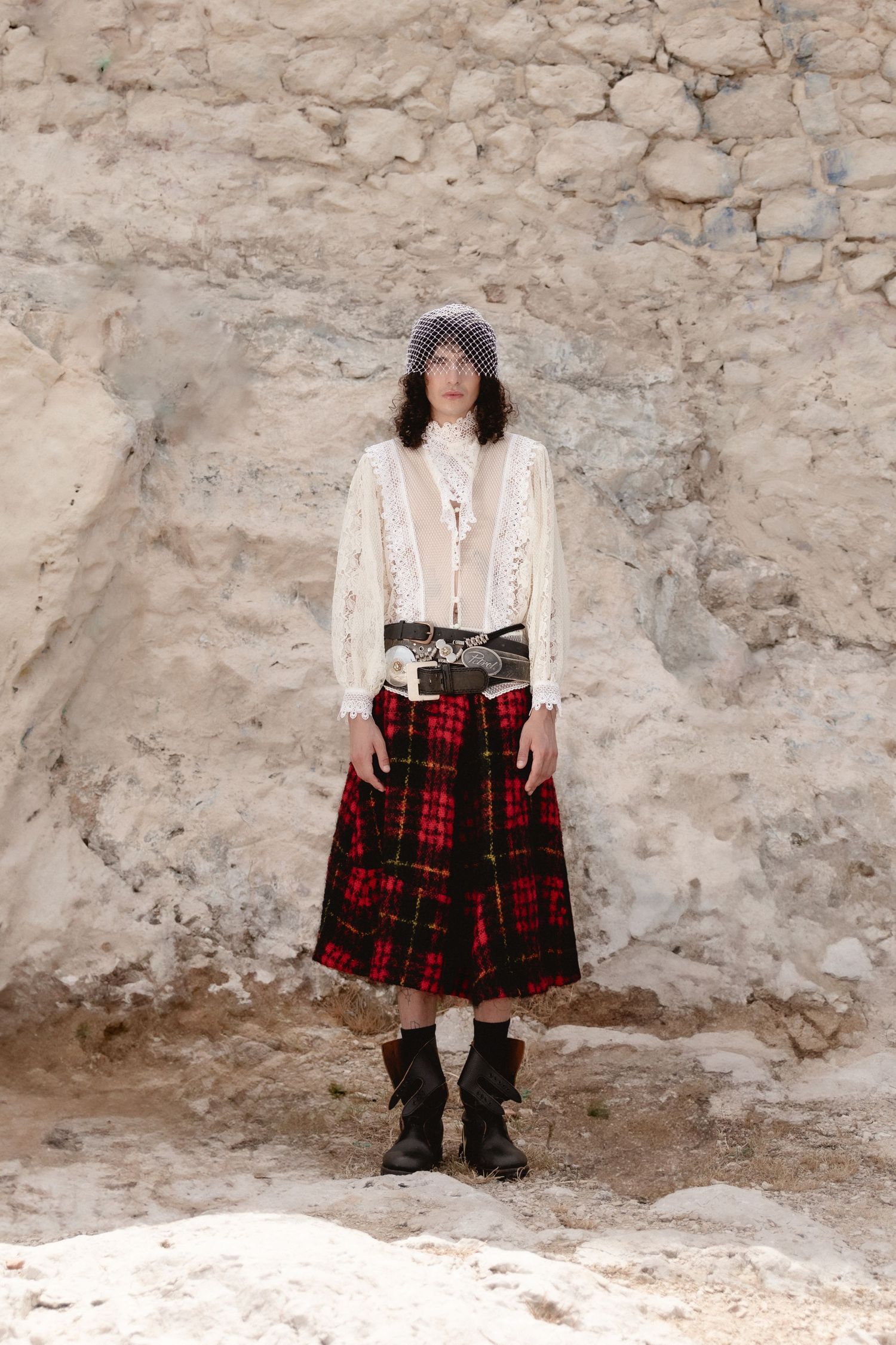 A series of photos showing a person in a white top and red plaid skirt against a textured stone wall.
