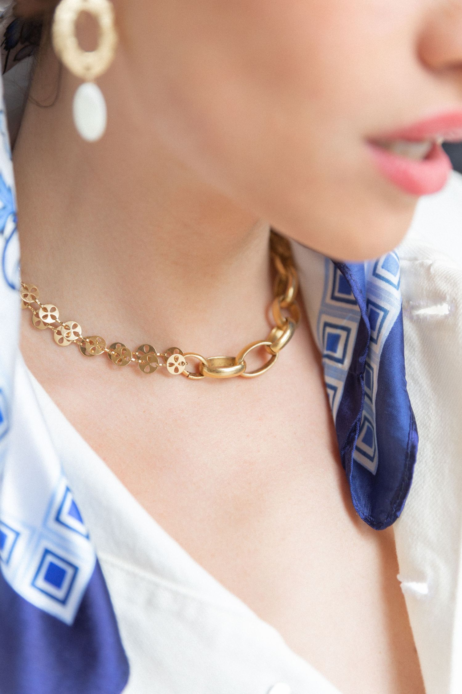 Elegant gold chain necklace and statement earring styled with blue geometric print scarf.