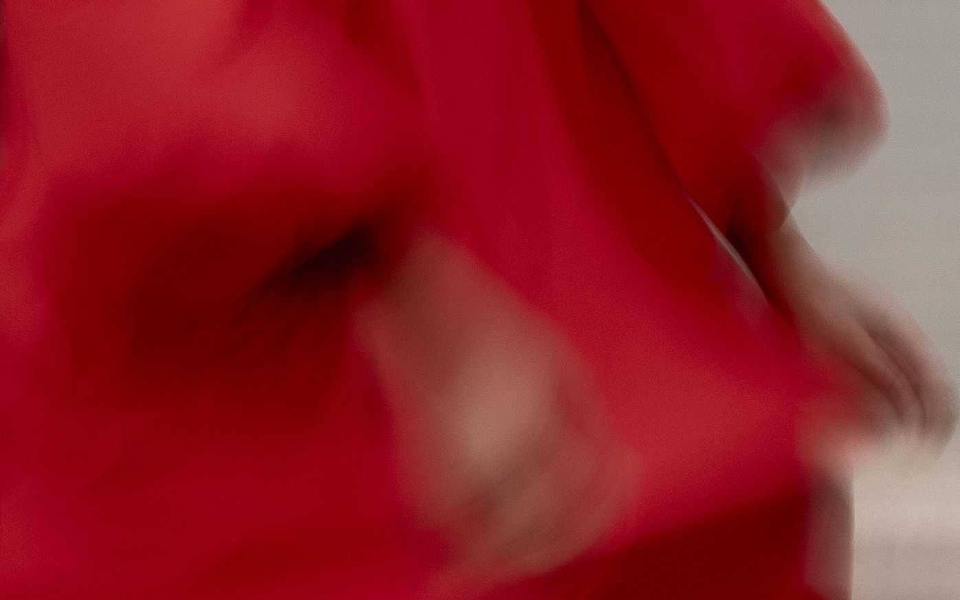 Red rose petals create an abstract pattern of soft textures and vibrant color against a light background.