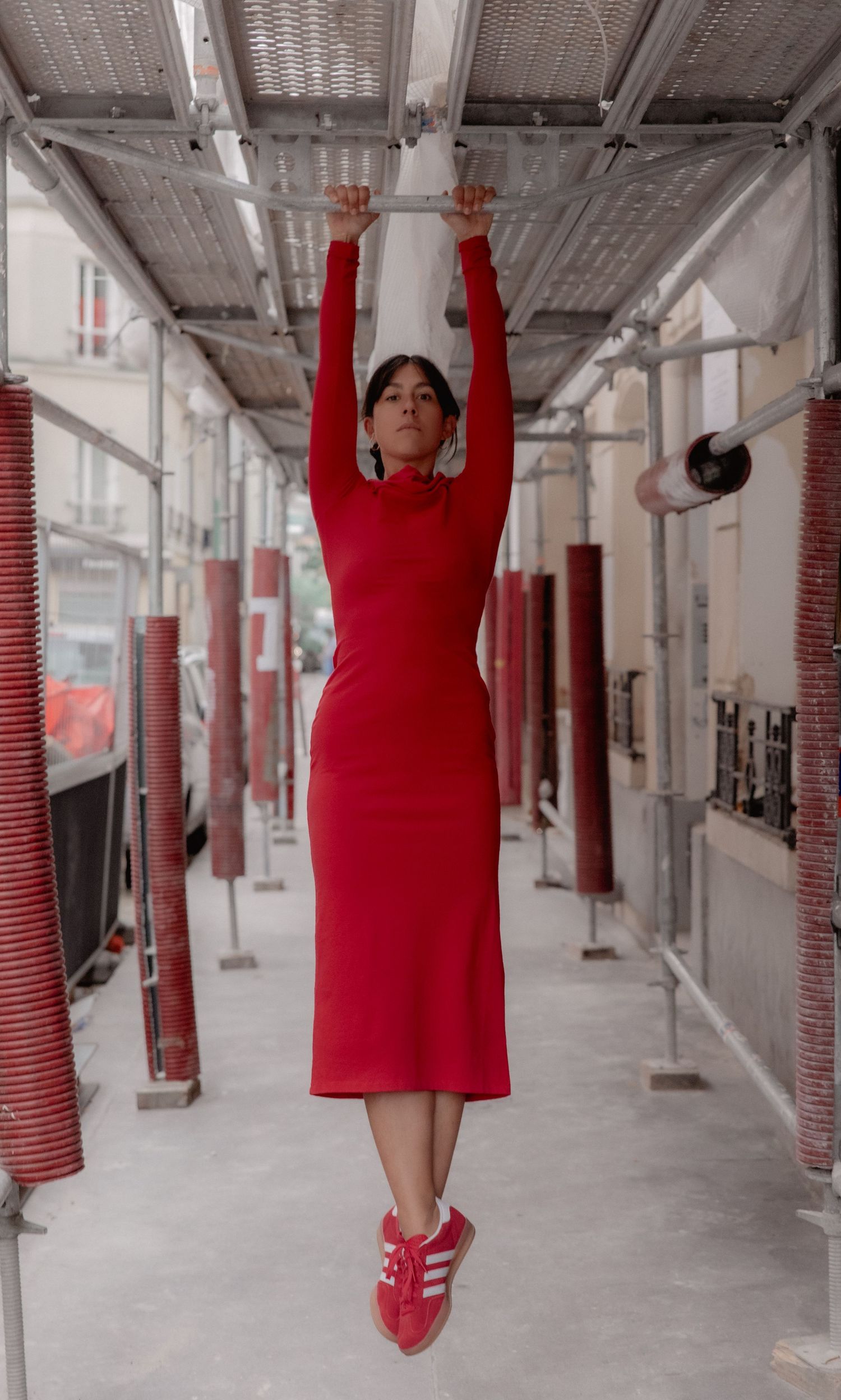 A series of four artistic photos showing someone in red clothing posing against a minimalist industrial corridor background.