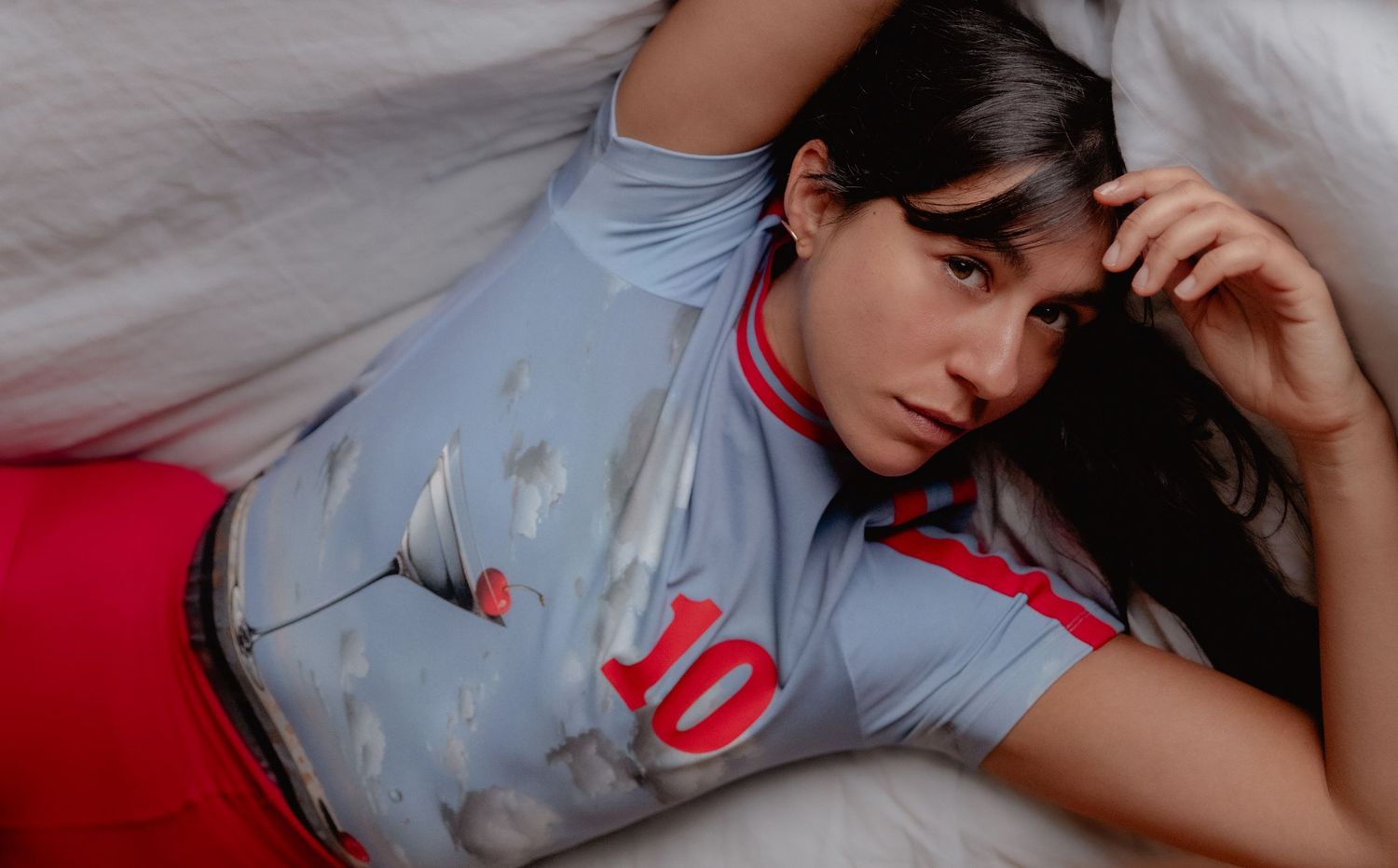 Person in light blue t-shirt lying on white bedding in various reclining poses.