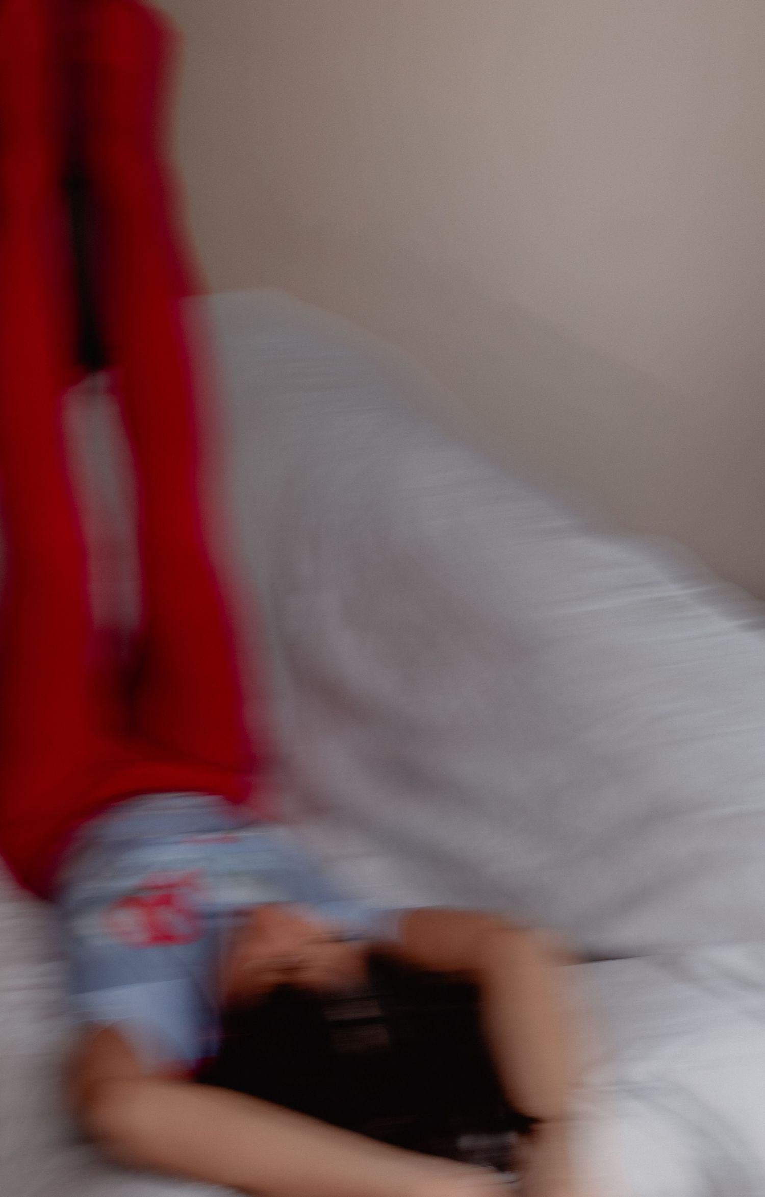 Person lying on white sheets with red curtains or drapes visible in the background.