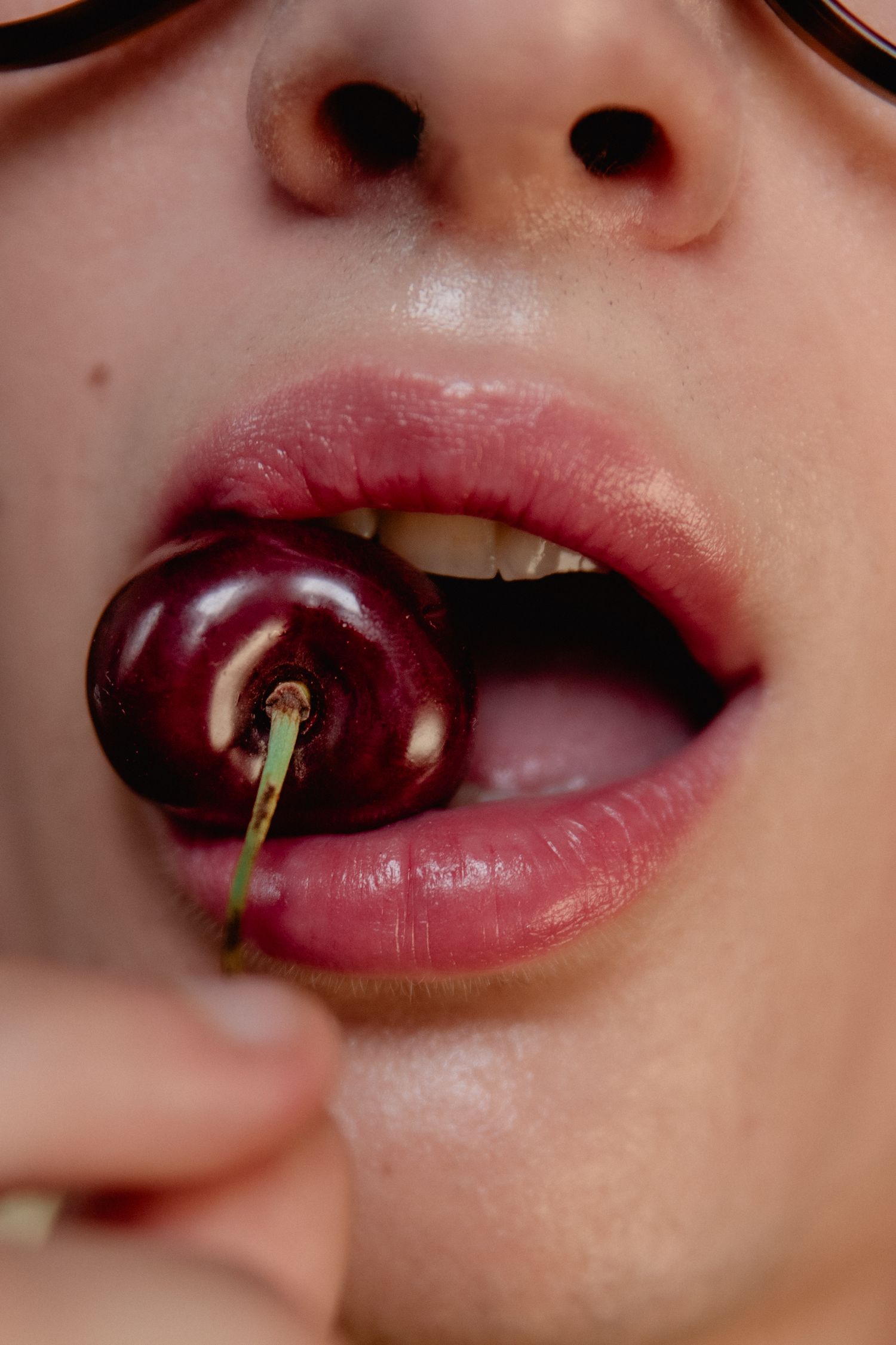 Close-up view of lips holding a cherry stem in a sequence showing how to tie a knot with the tongue.