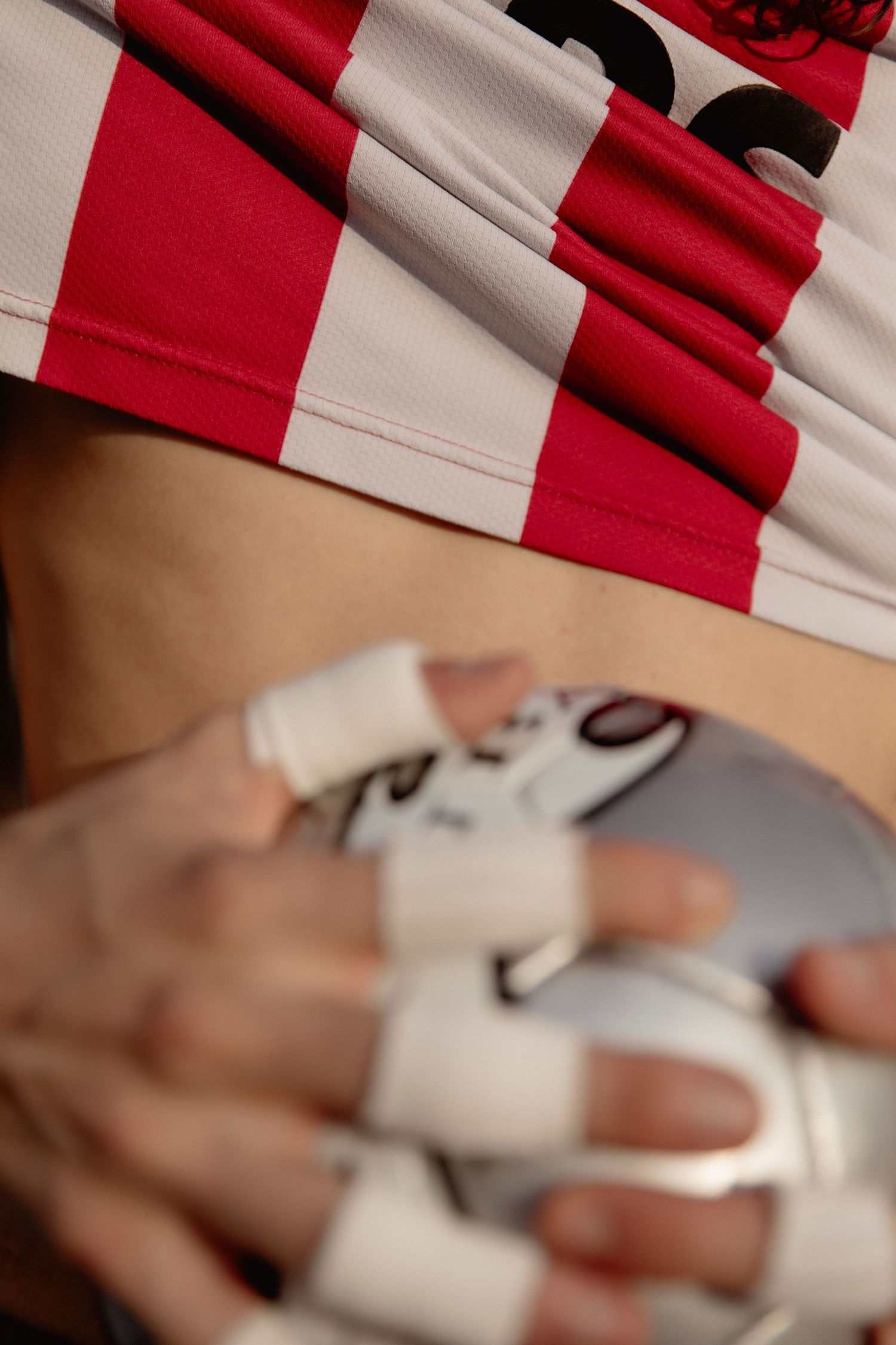 Close-up view of hands holding a white Xbox controller against a red and white striped background.