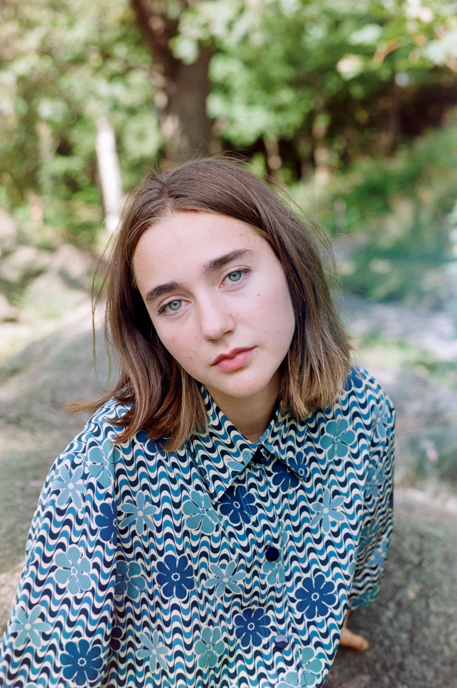Portrait of person wearing blue and white chevron patterned shirt outdoors.