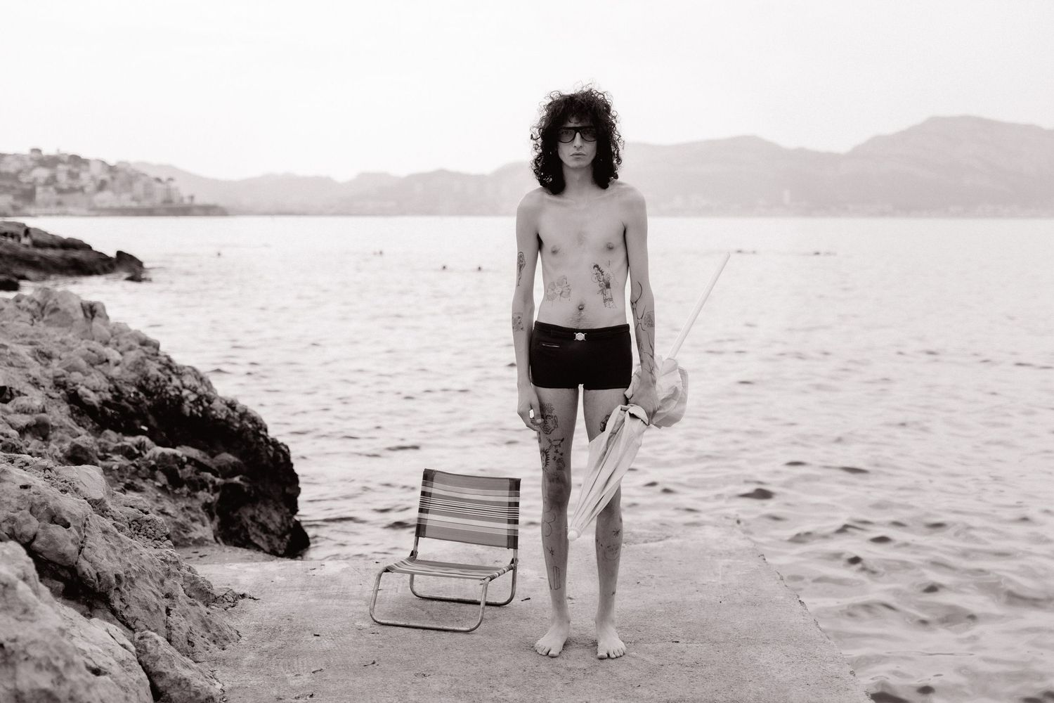 A series of black and white beach photographs showing people walking and relaxing along a rocky coastline.
