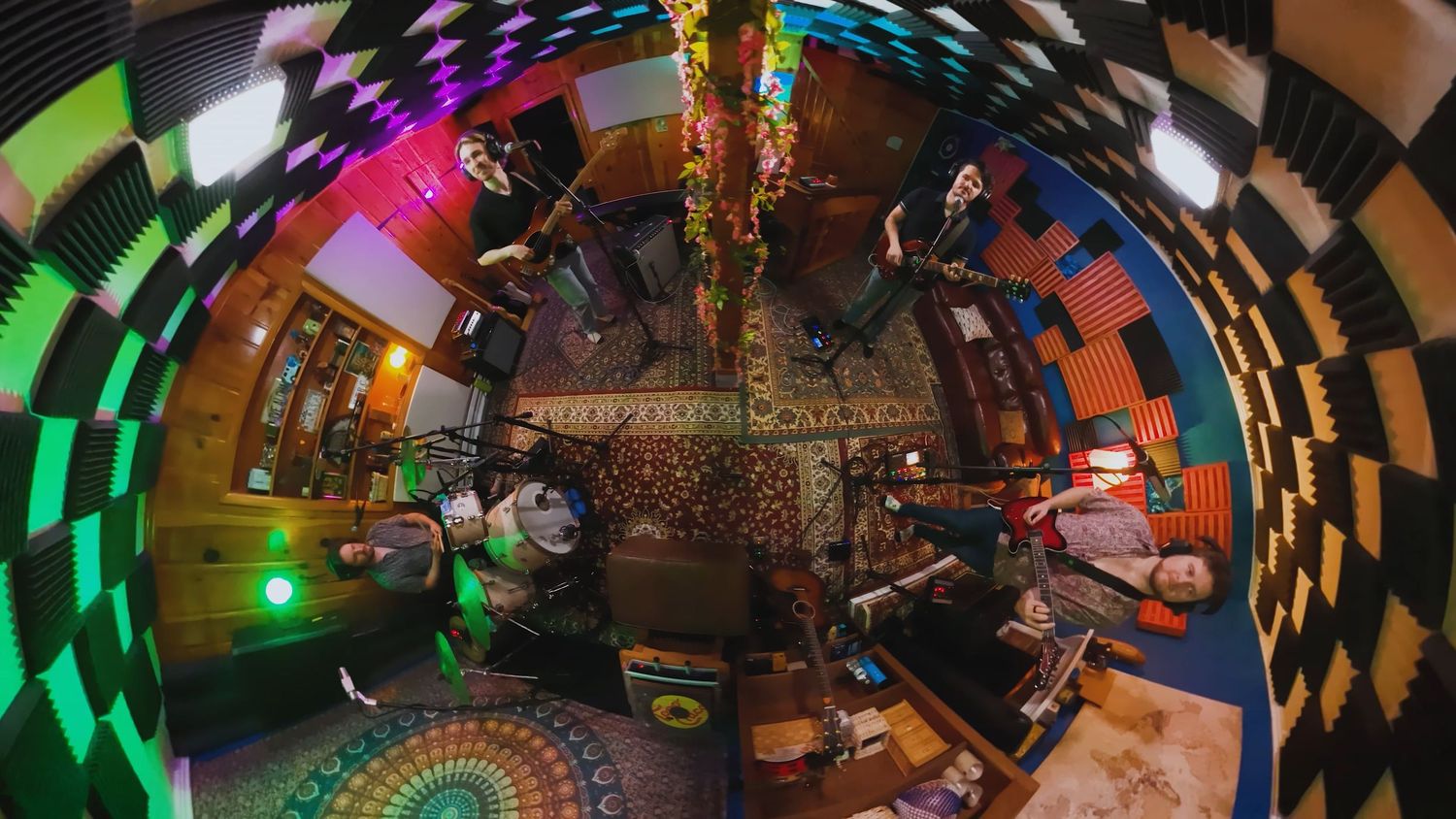 A fisheye lens captures a colorful music studio with vibrant lighting and musicians in a 360-degree view.
