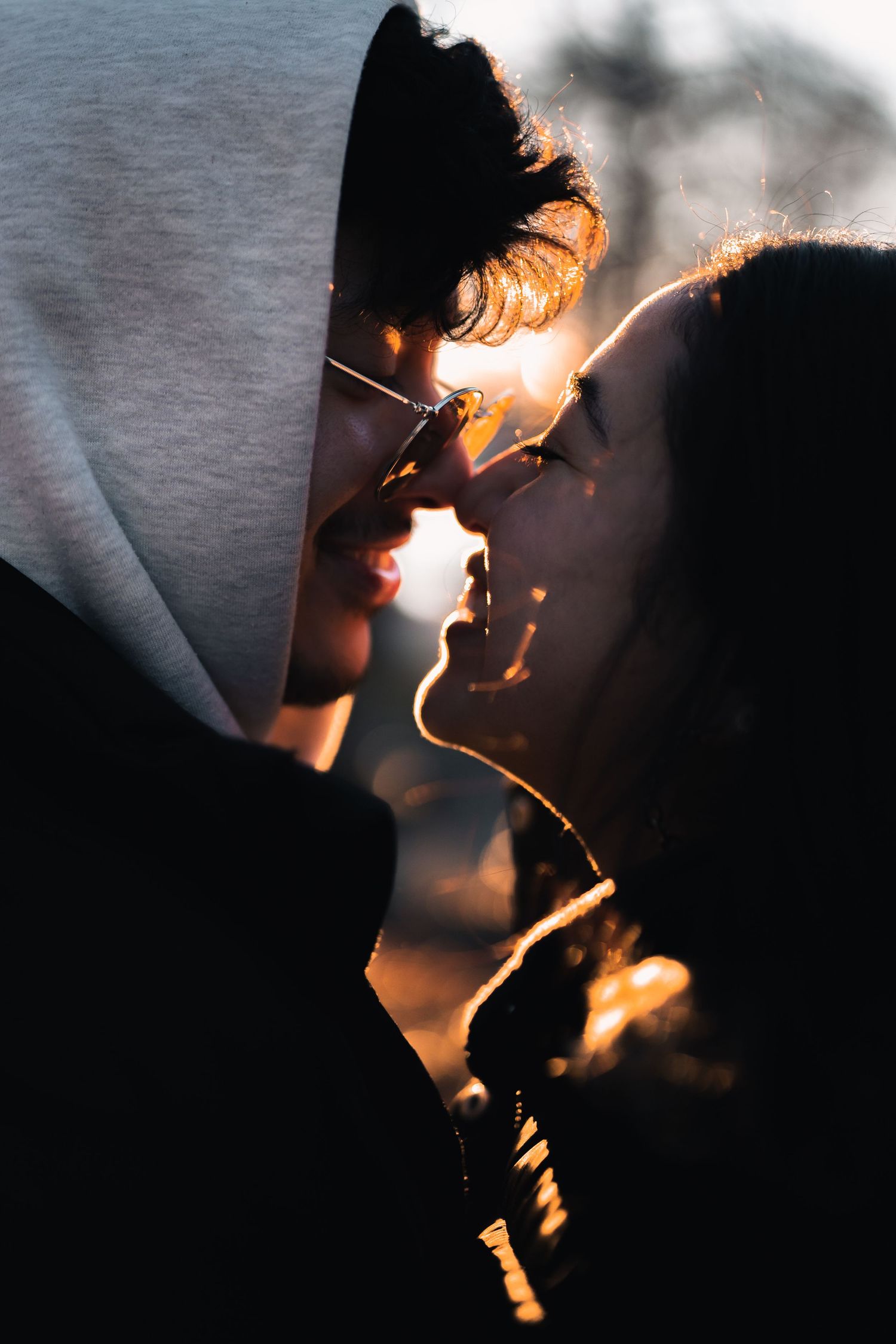 Romantic couple sharing an intimate moment with golden backlight creating a glowing silhouette effect.