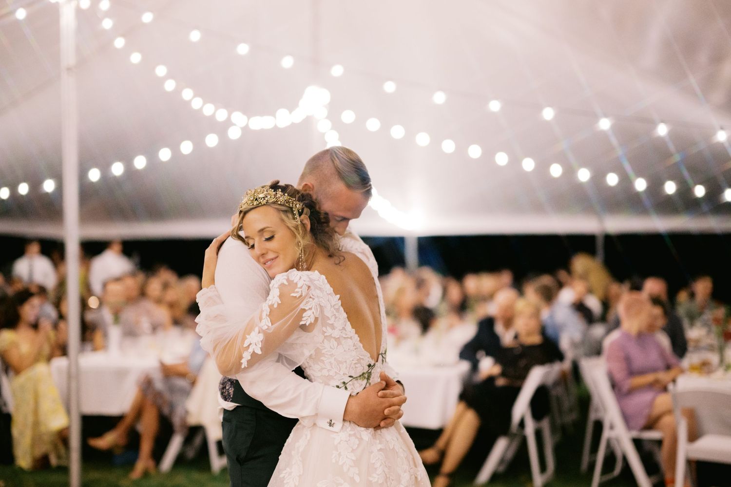 A romantic first dance under twinkling lights at an outdoor wedding reception.
