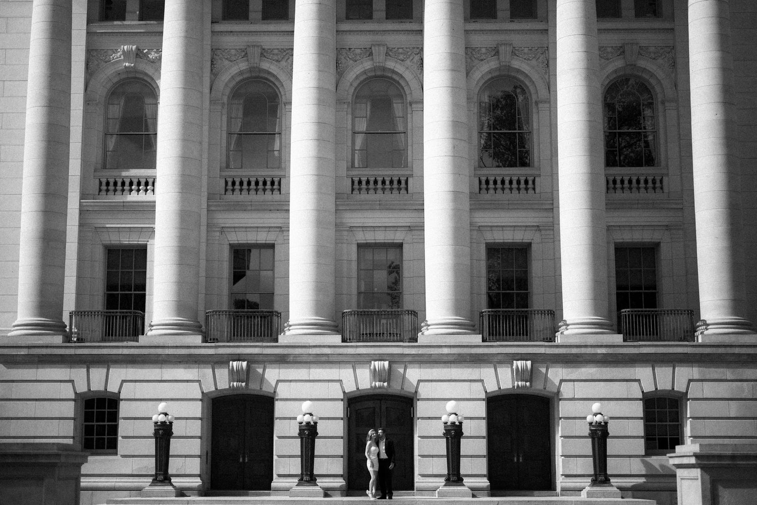 Wide shot of a neoclassical building facade with massive white columns and arched windows.