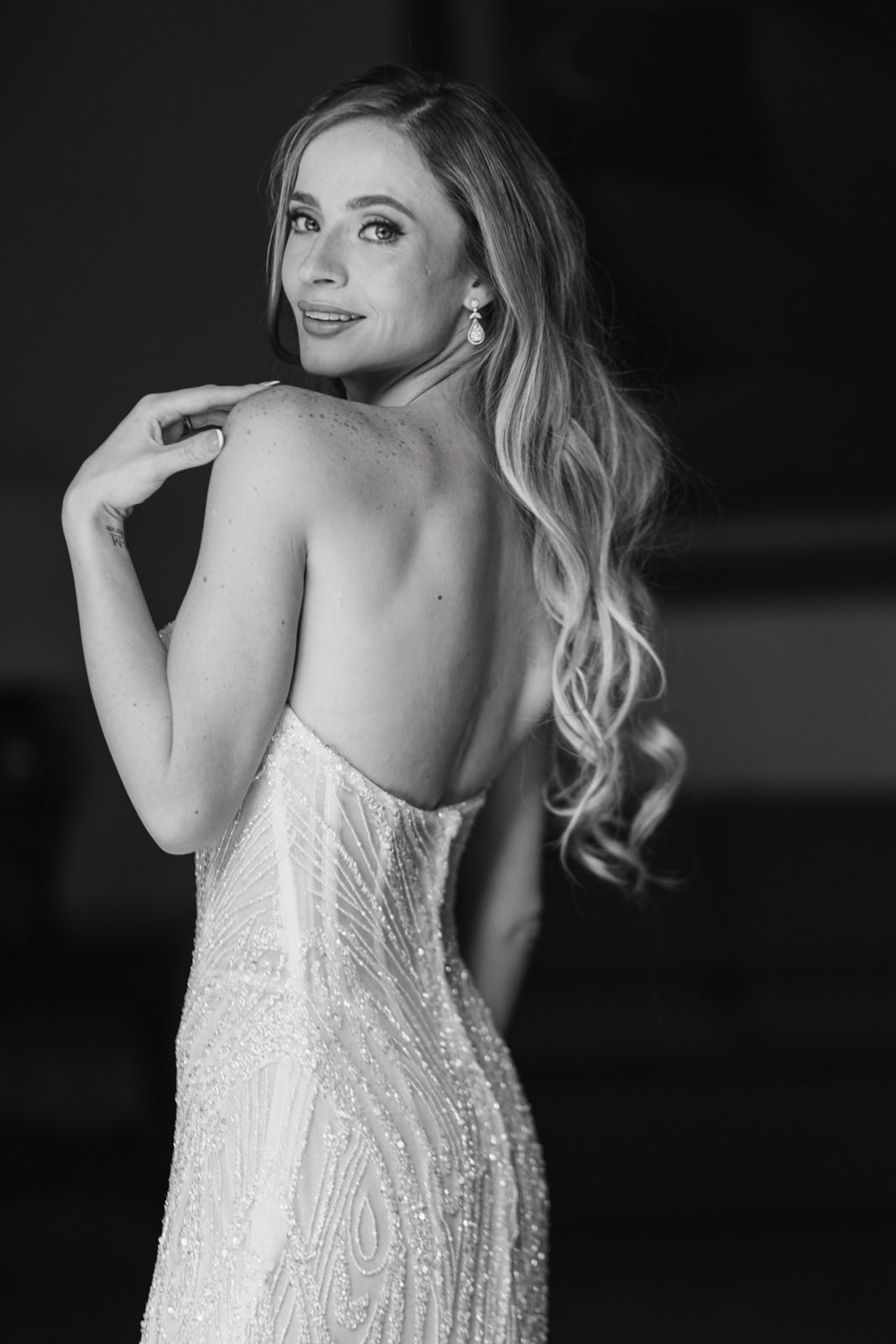 Black and white photo of a blonde woman in a backless sequined gown, looking over her shoulder elegantly.