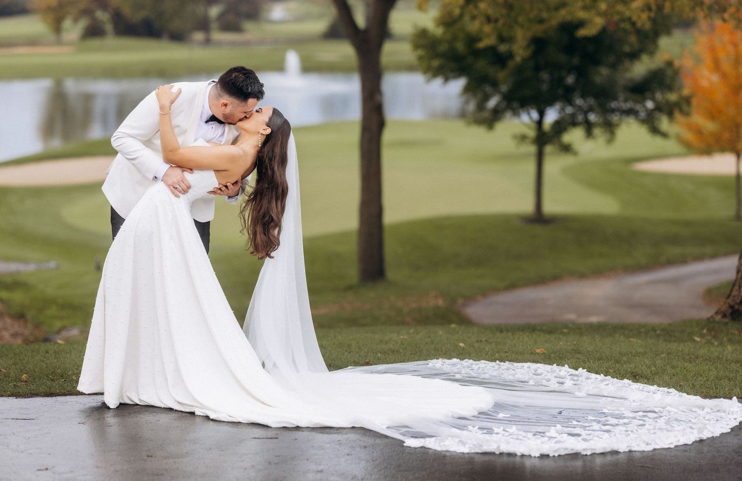 A couple in wedding attire embraces on a scenic golf course path during their special day.