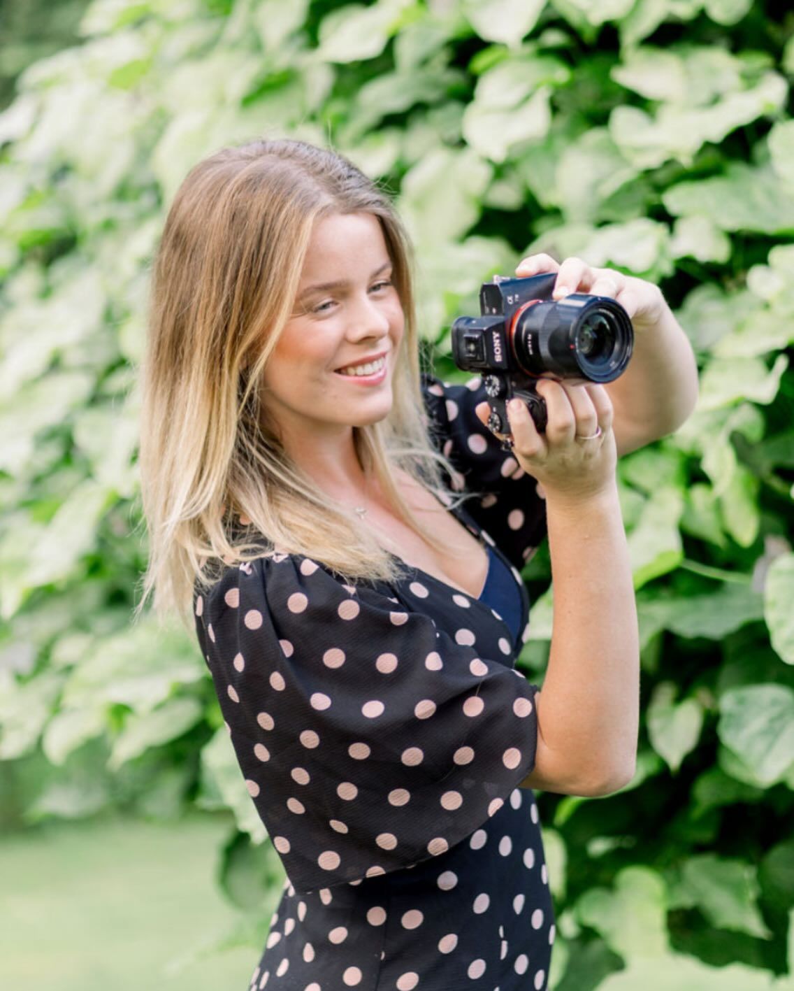 UK-based wedding photographer in Nottingham holding a camera, capturing my editorial storytelling and a soft, romantic light-filled style.