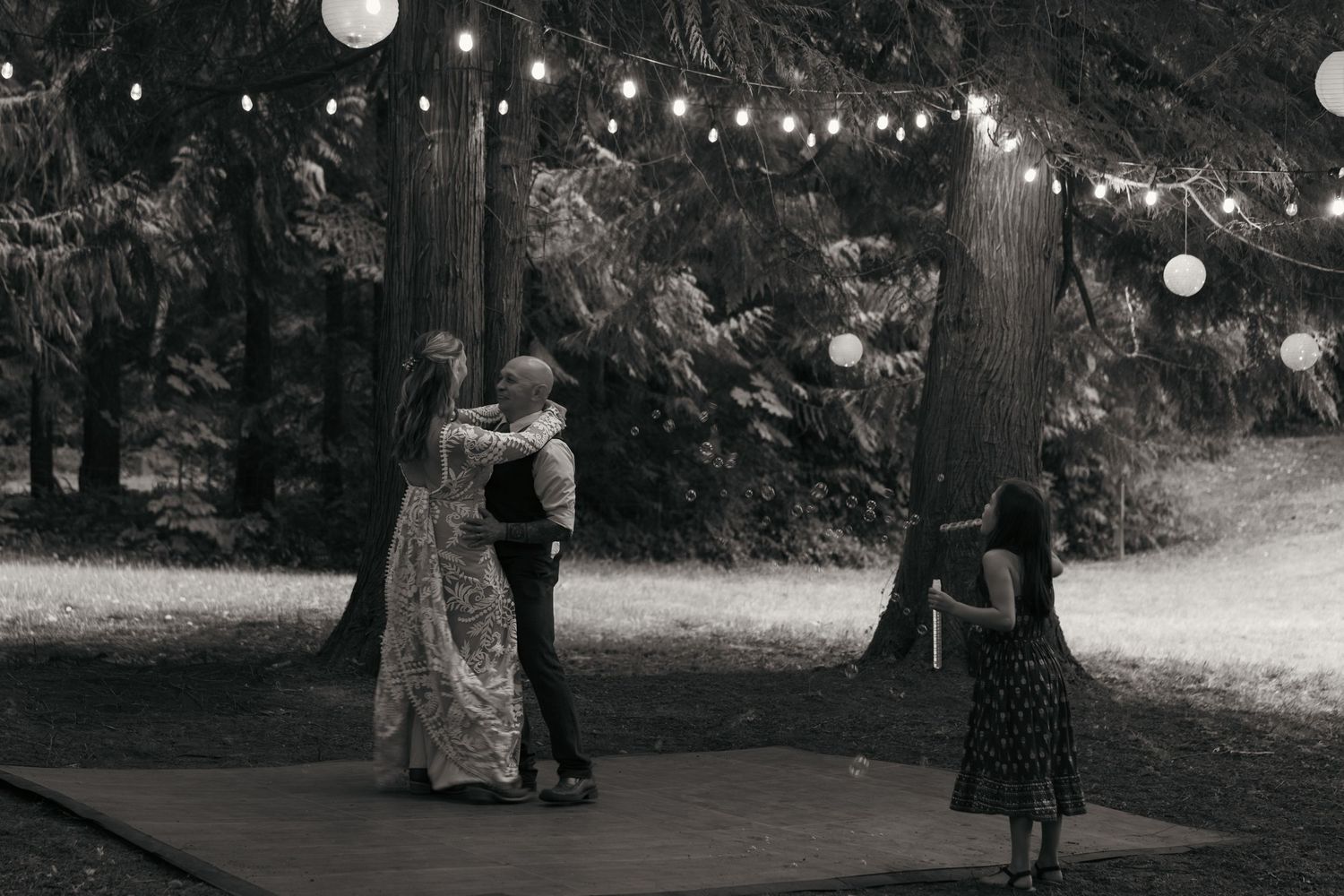 Black and white photo of couple dancing outdoors at night under string lights, Captured by Savvy Photography