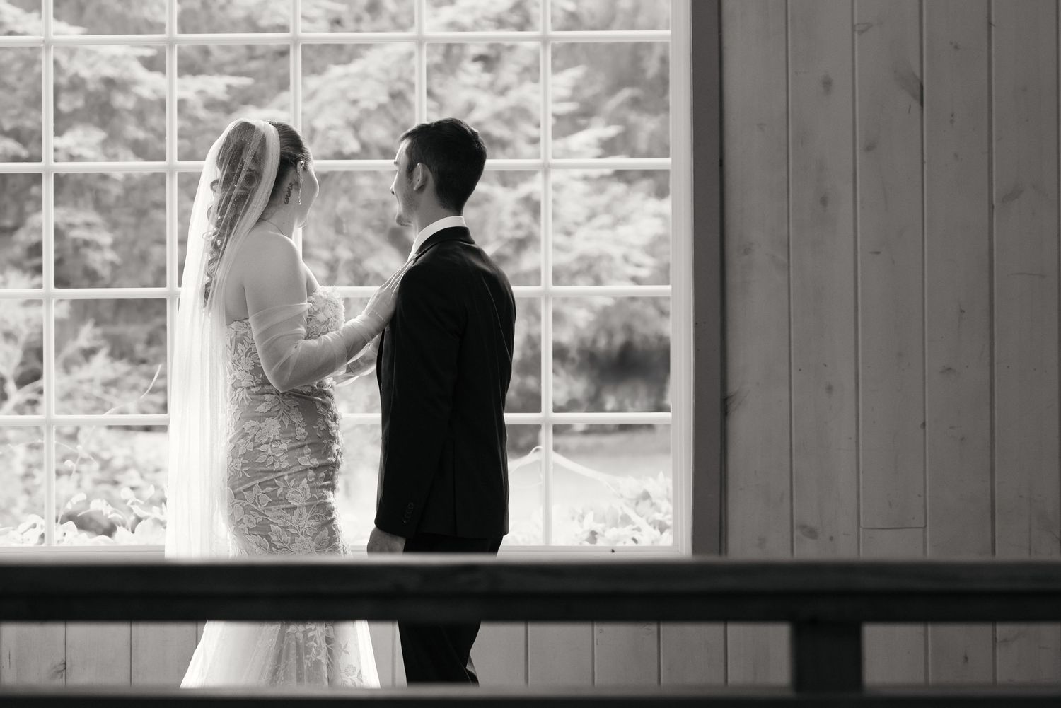 A bride and groom share intimate moments in black and white wedding photos against a rustic wooden backdrop. Captured by Savvy Photography