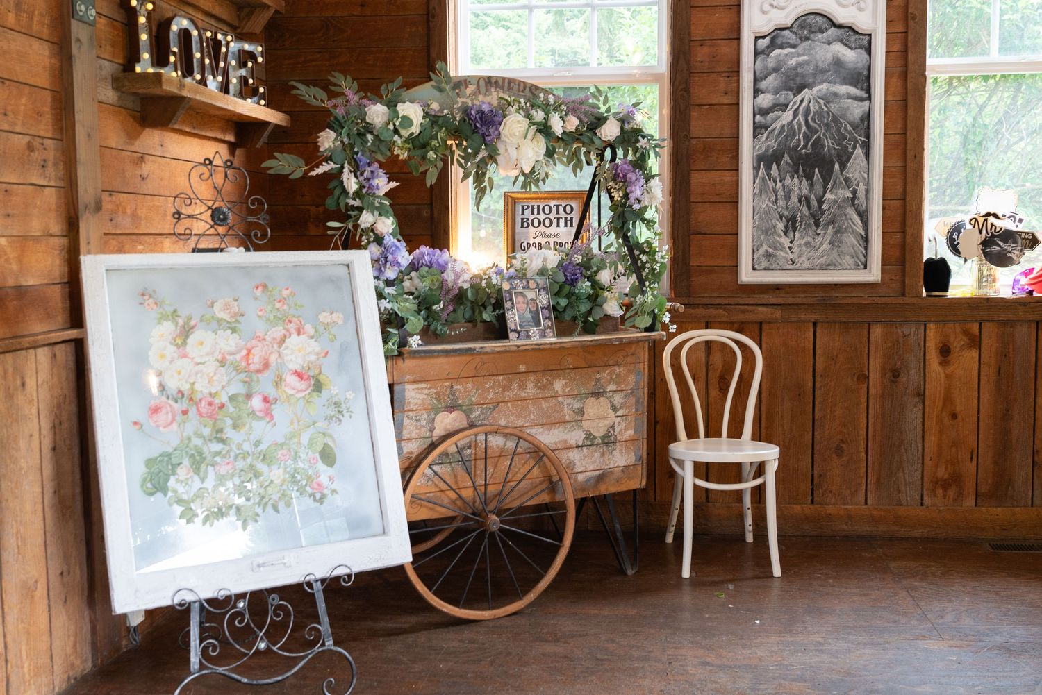 A rustic wooden barn interior decorated with vintage artwork and floral arrangements along the wall. captured by Savvy Photography - Seattle