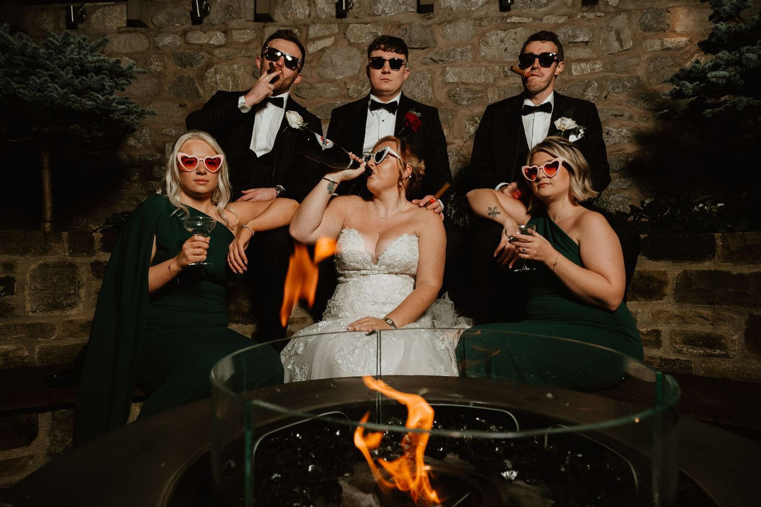 Wedding guests enjoy cocktails and conversation in a rustic stone venue with dramatic lighting and ambiance.