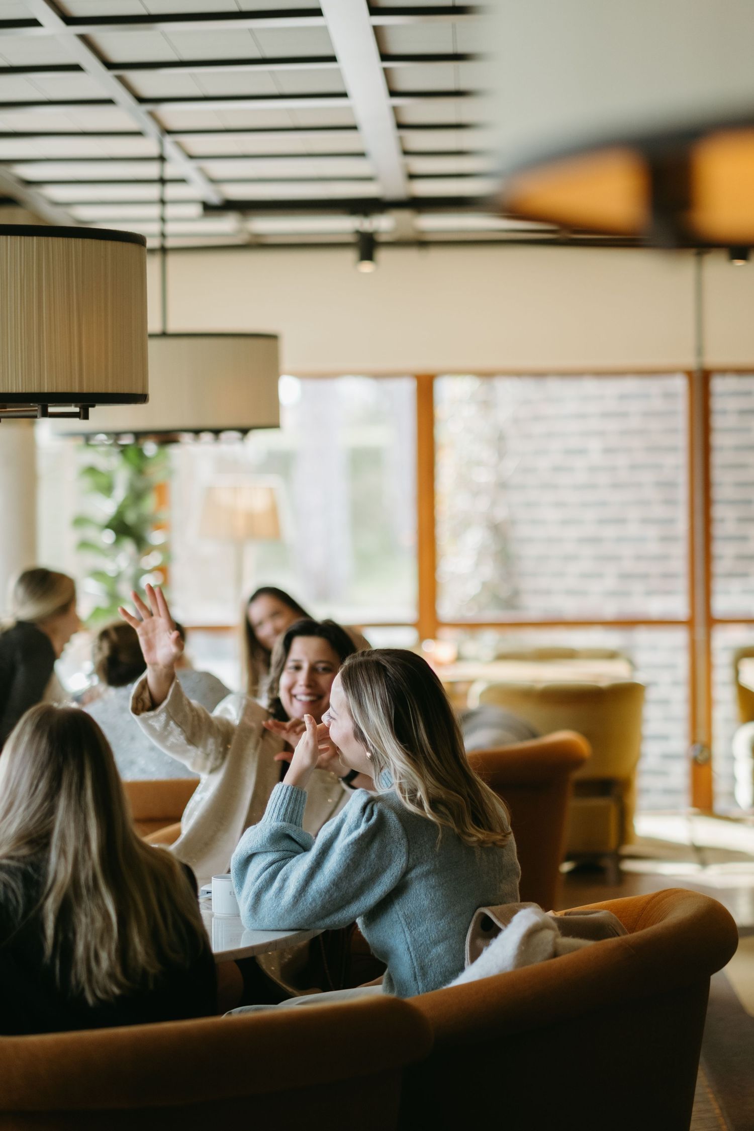 women sitting in lunch area of Ellery Beach House and laughing while being captured by corporate event photographer in Stockholm