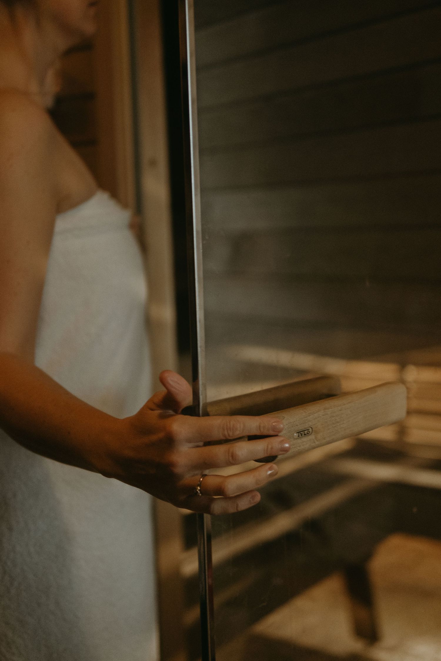 a detail of woman's hand opening door to sauna being captured by lifestyle photographer in Stockholm