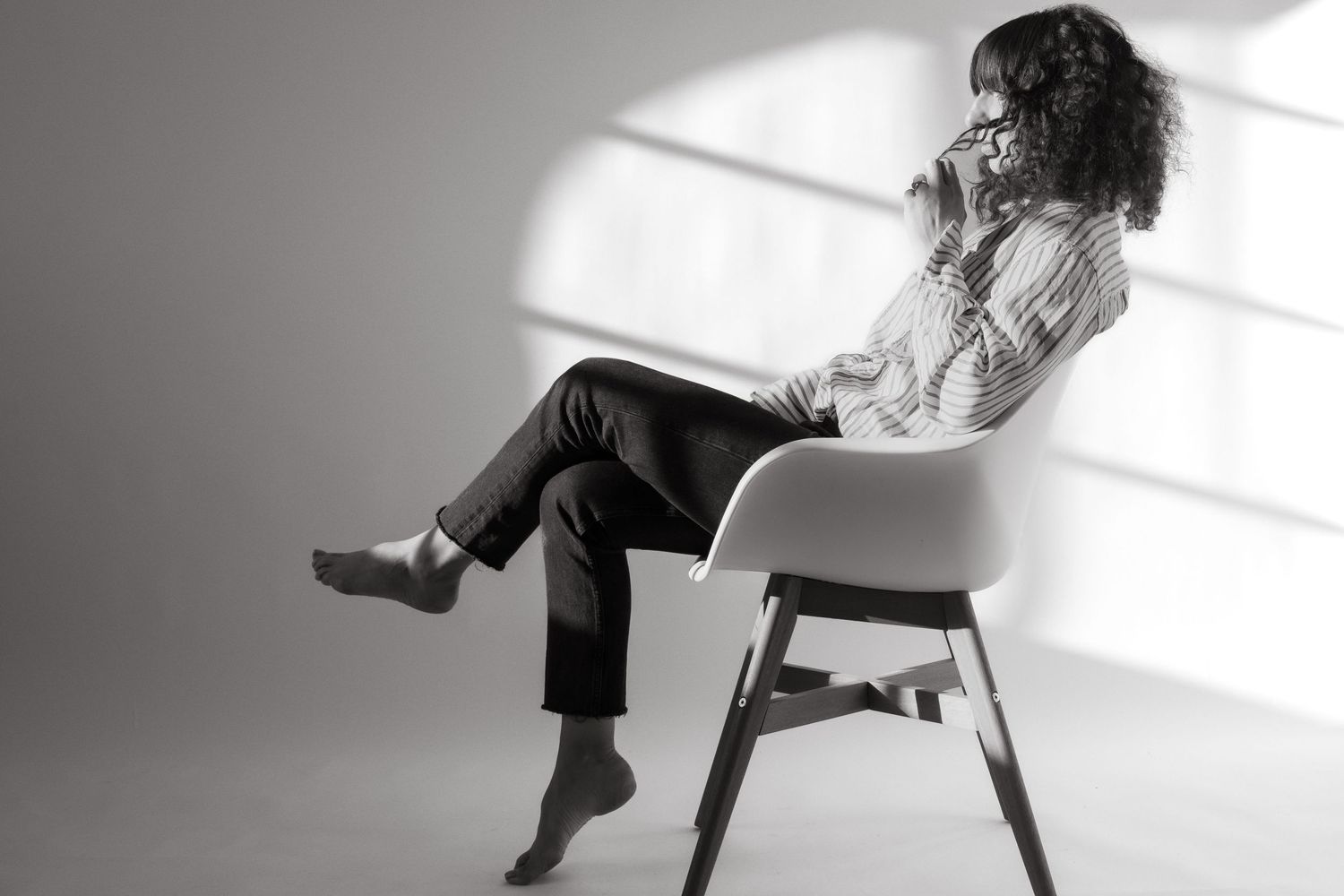 Stockholm event photographer sits in a chair looking out a window and playing with her hair
