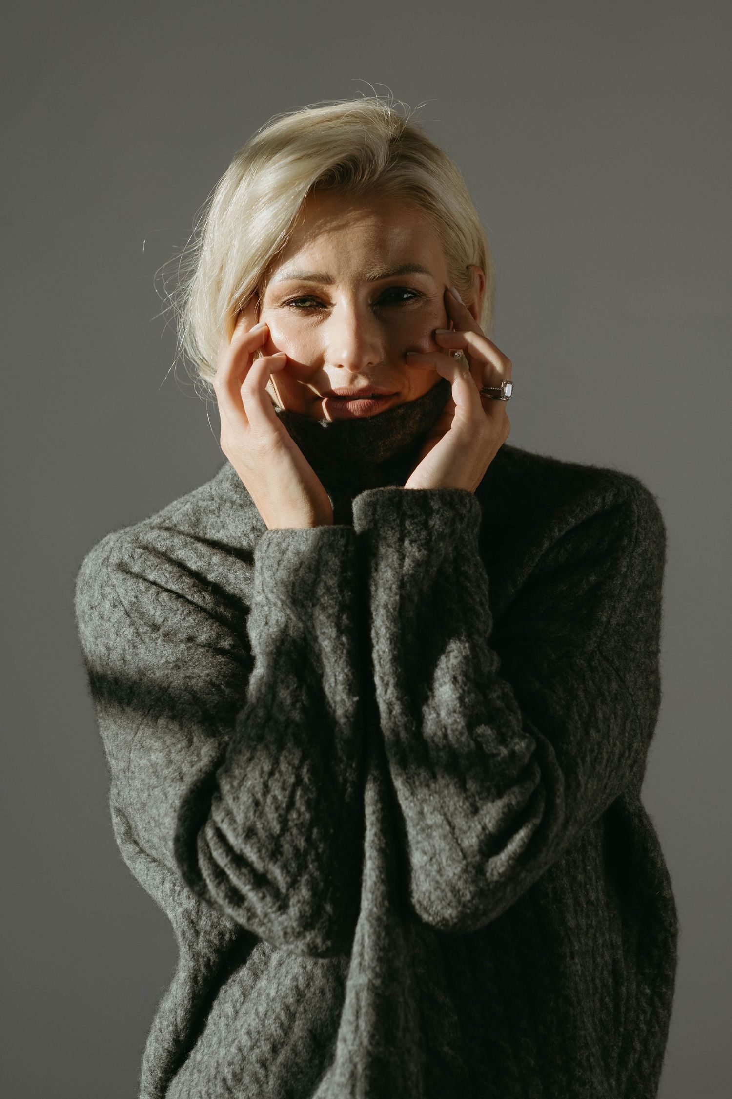 woman touching her face and looking into camera while being captured by Stockholm personal branding photographer