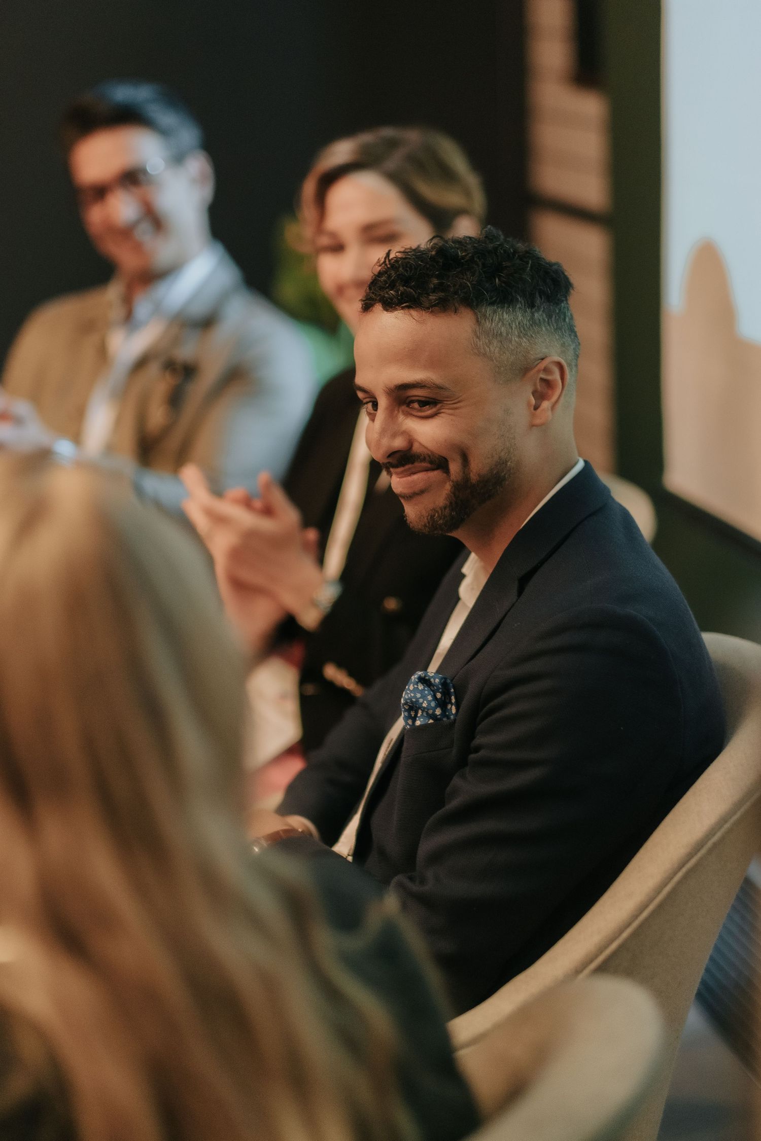 man during a conference, looking at his fellow speakers and smiling while being captured by business photographer in Stockholm