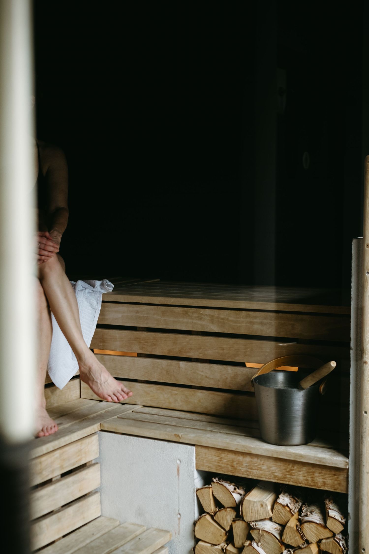 detalj av kvinnans ben när hon sitter i bastun i mörkret medan hon fångas av livsstilsfotograf i Stockholm