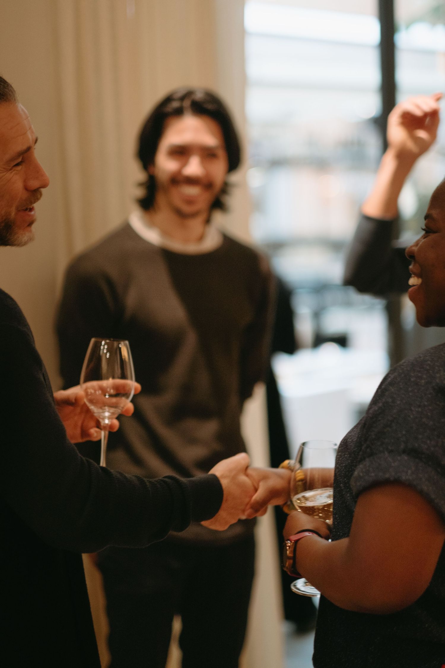 man and woman shaking hands while both holding their glass of wine while being captured by event photographer in Stockholm