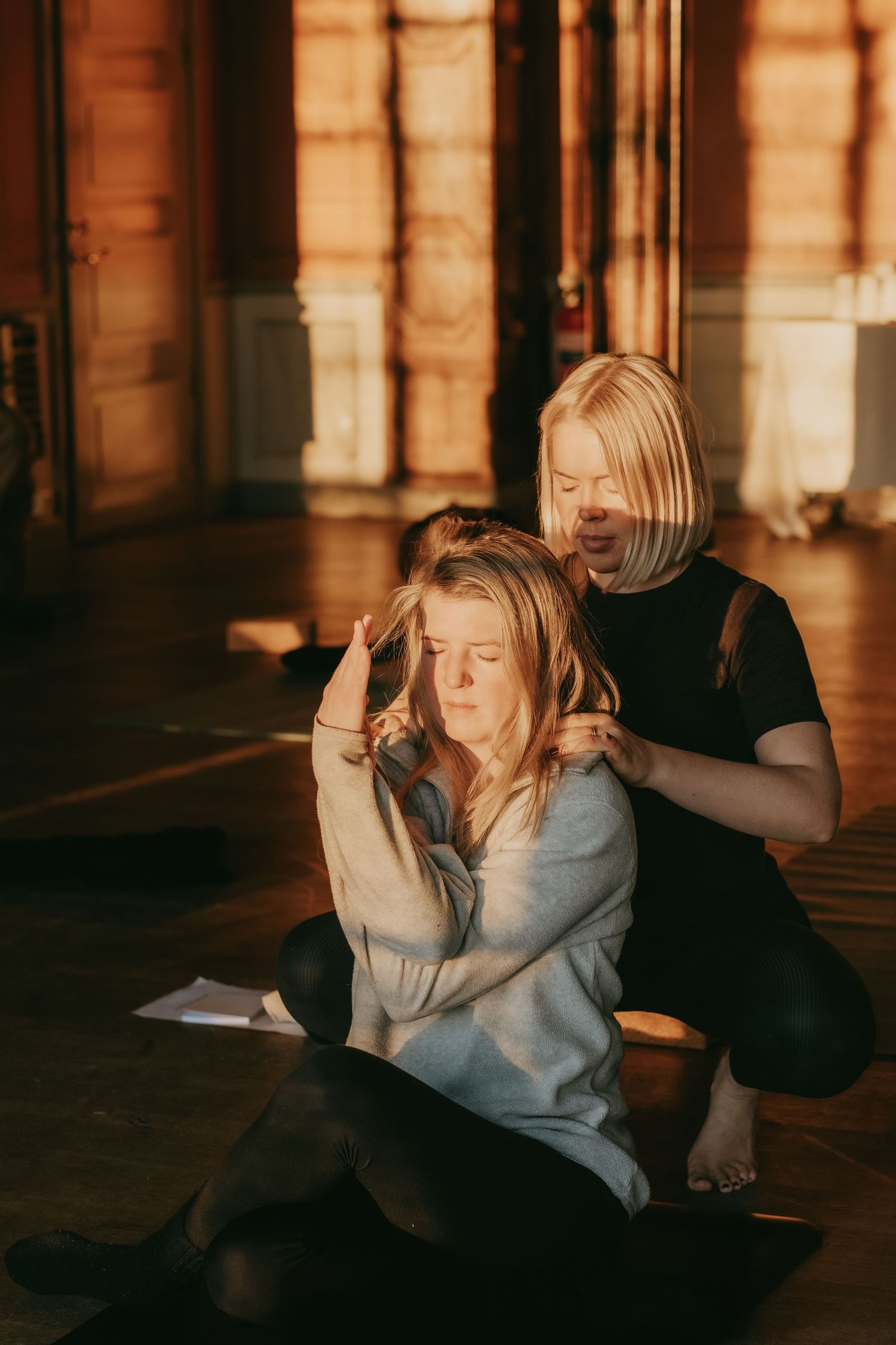 en yoga lärare hjälper en kvinna med yoga pos medan de fotas av retreat och yoga fotograf i Stockholm