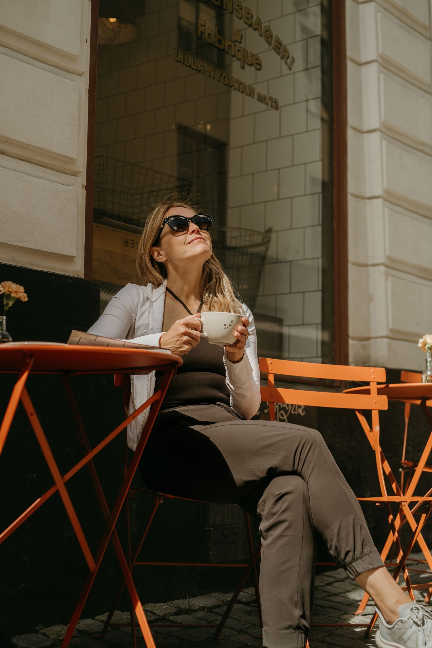 a woman sitting in a café enjoying a cup of coffee while being captured by personal branding photographer in Stockholm