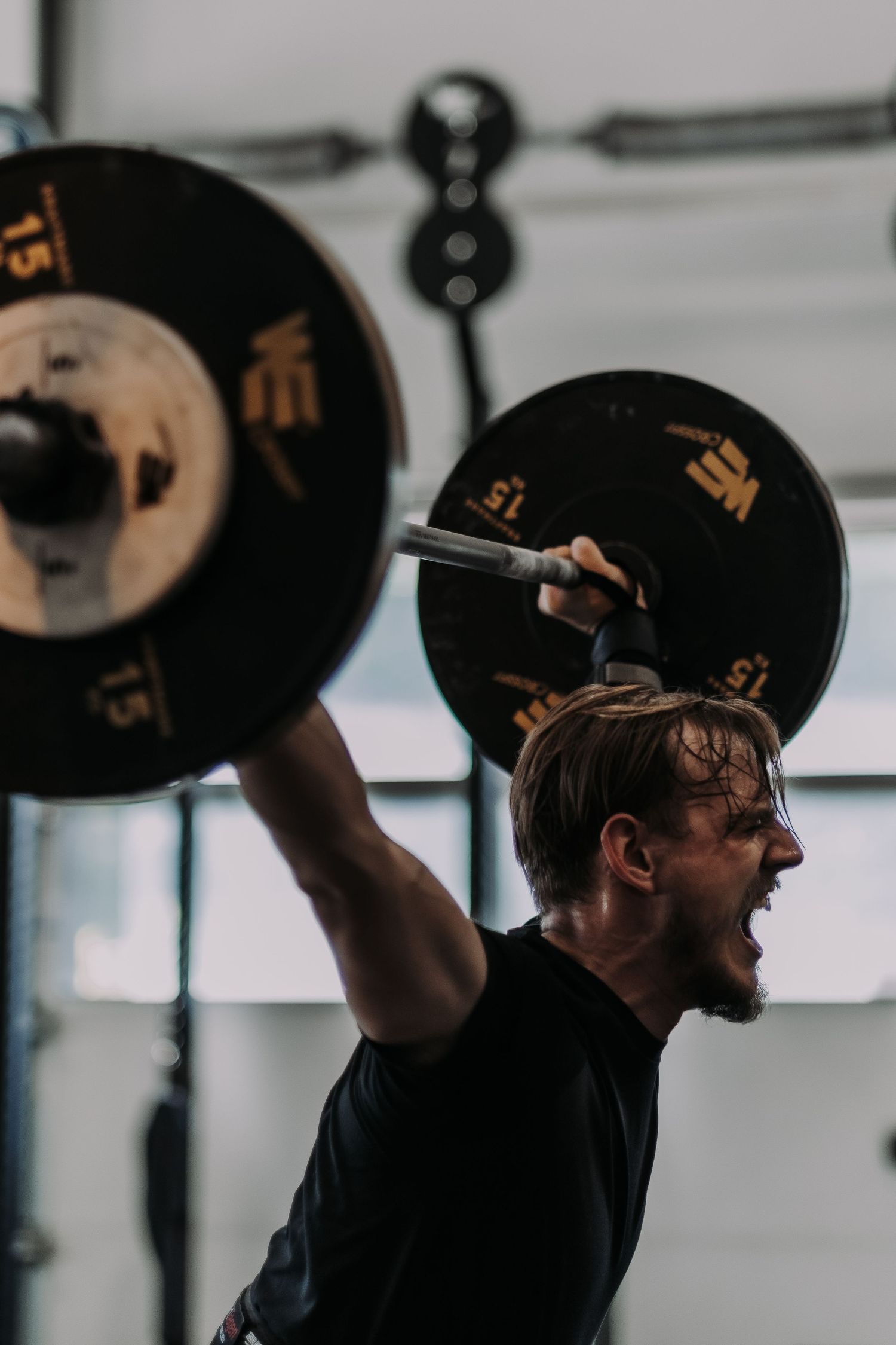 a man screaming in effort while lifting heavy weights above his head while being captured by lifestyle photographer in Stockholm