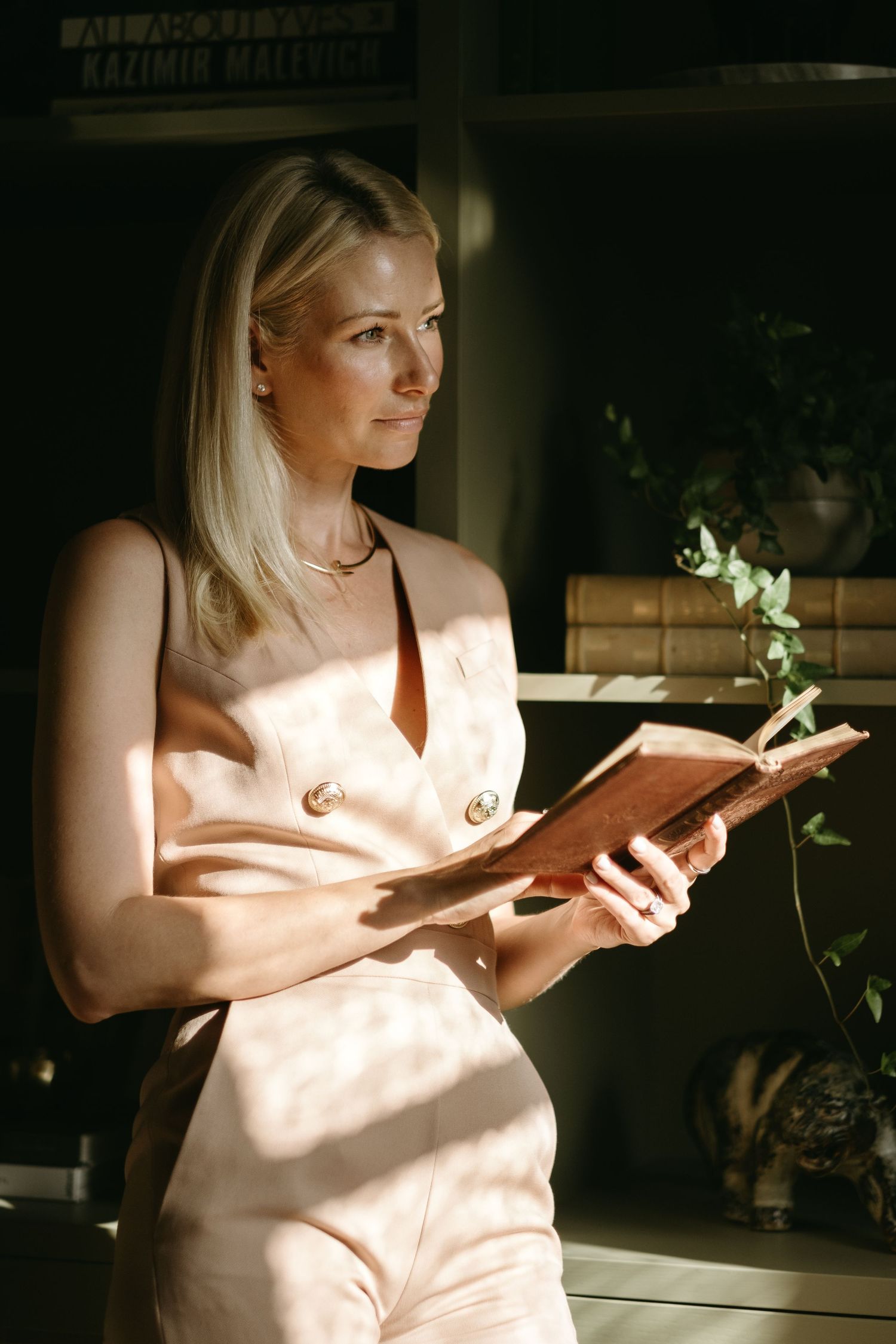 woman holding a book, standing near book shelves during Stockholm personal branding photoshoot