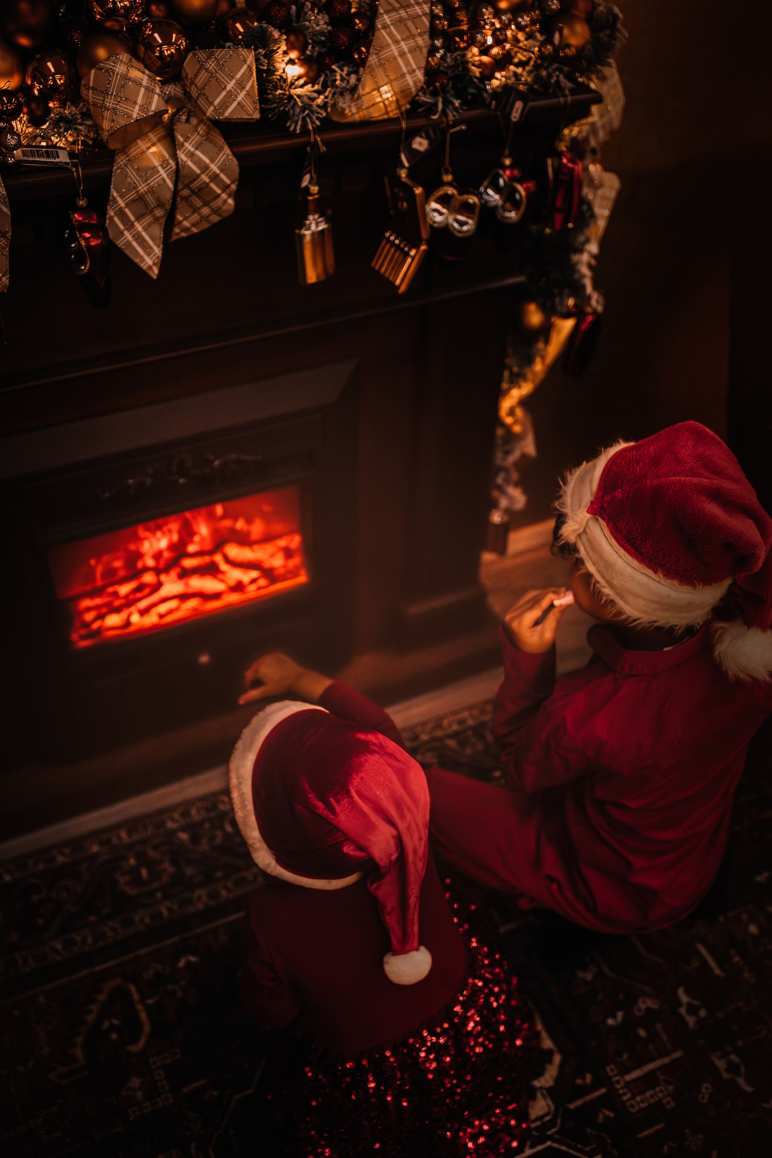 A cozy fireplace scene with Christmas stockings and decorative garland in warm lighting.