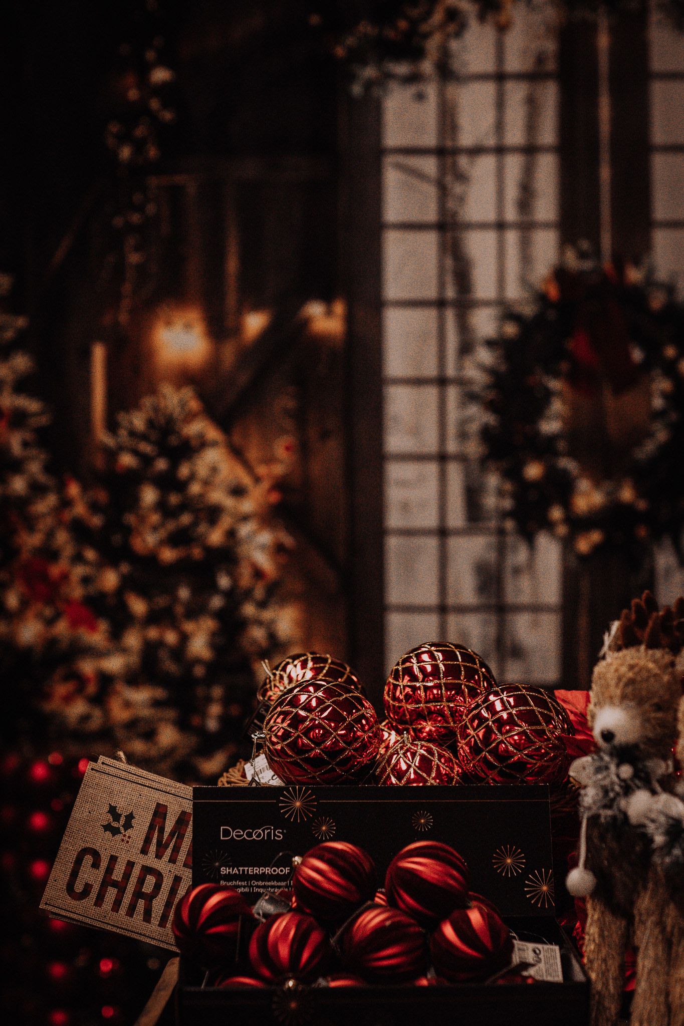 Red Christmas ornaments and decorations displayed in a cozy window setting with warm candlelight.