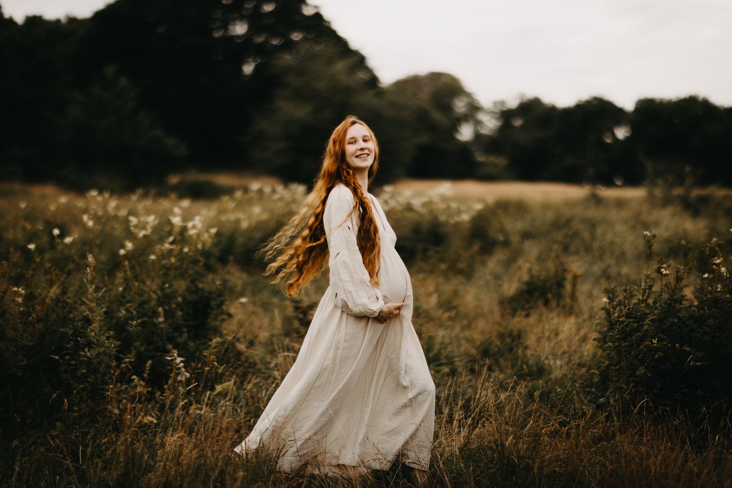 A person in a flowing white dress twirls in a golden field at sunset, creating a dreamy atmospheric scene.