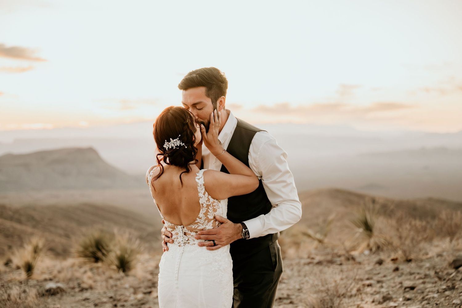 Romantic desert wedding portraits with mountains and sunset in background.