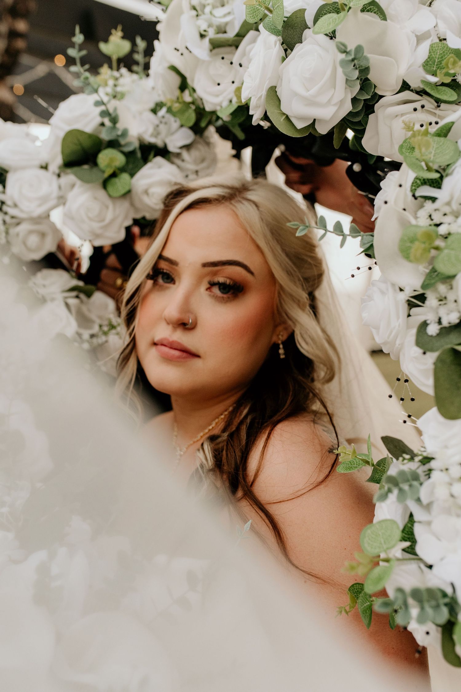 Delicate white roses and greenery create an ethereal floral crown arrangement.
