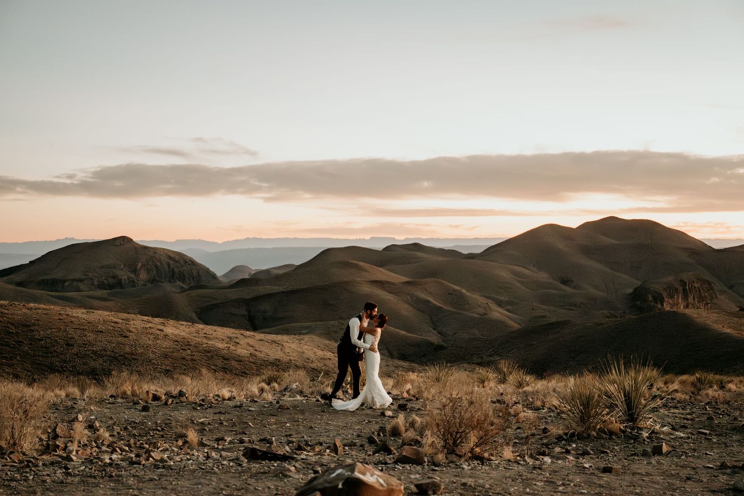 A panoramic view of a desert landscape with rolling hills and mountains at sunset in warm golden light at Sotol Vista in Big Bend NP.
