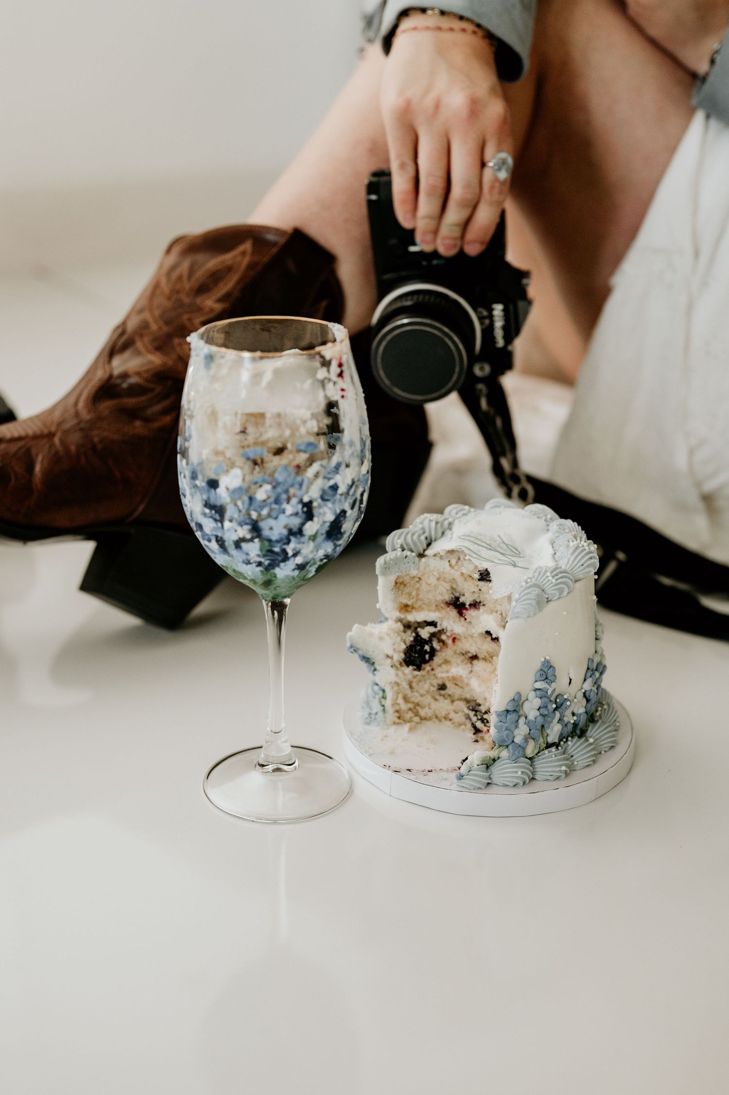 Wine glass and cake displayed on white surface with elegant styling details.