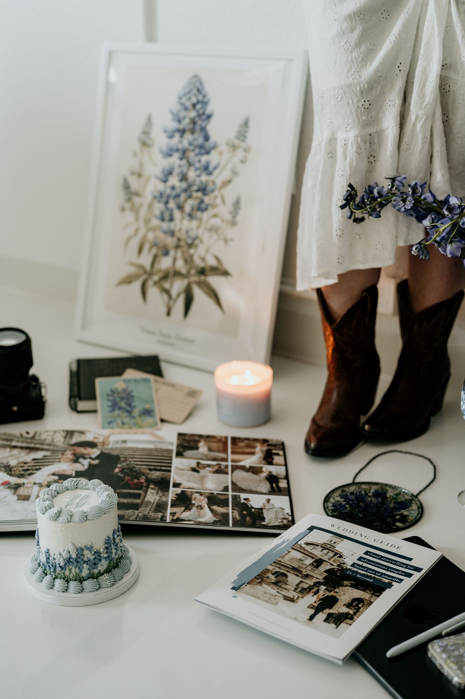 Vintage-style display with botanical prints, candles, and photo albums on white surface.