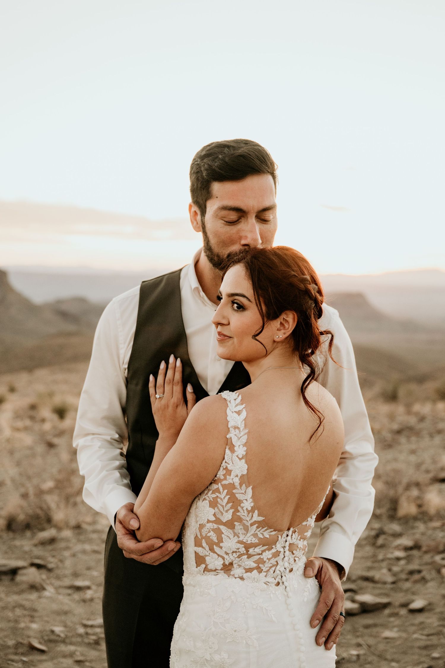 Romantic wedding portraits captured in a desert setting with soft sunset lighting.