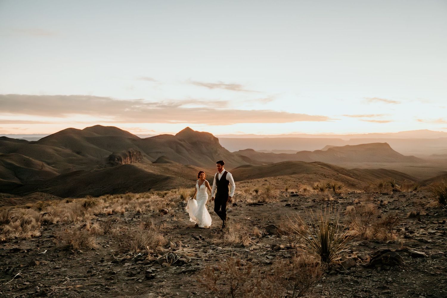 Panoramic desert mountain landscape with couple at sunset.